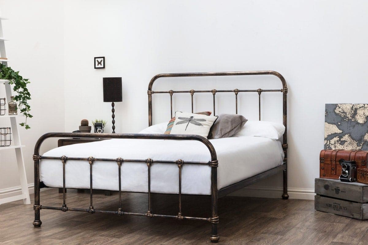 aged black metal bed frame in white bedroom with timber floorboard and vintage styling