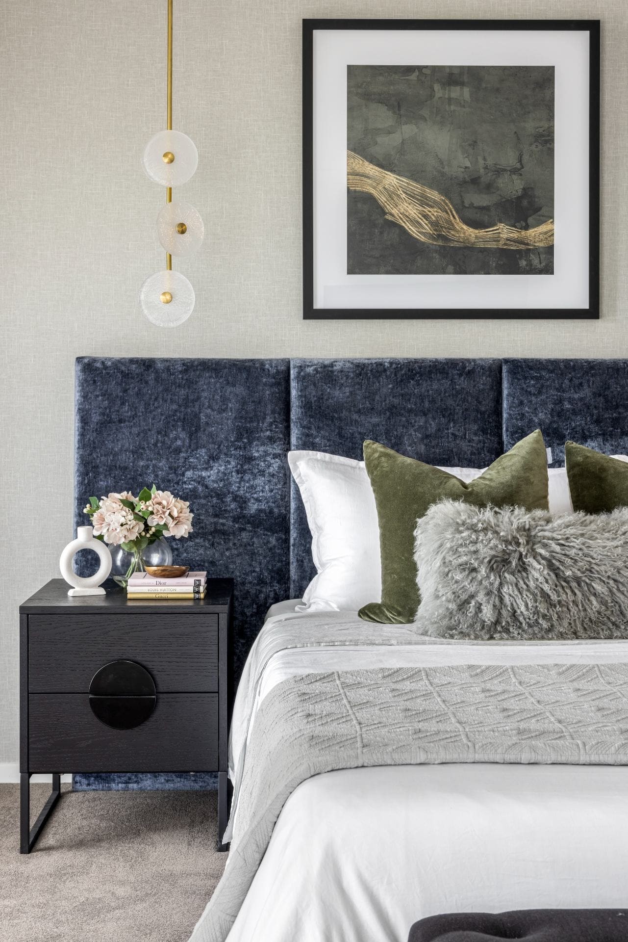 bedroom with blue velvet extra wide headboard black bedside tables and grey wallpaper