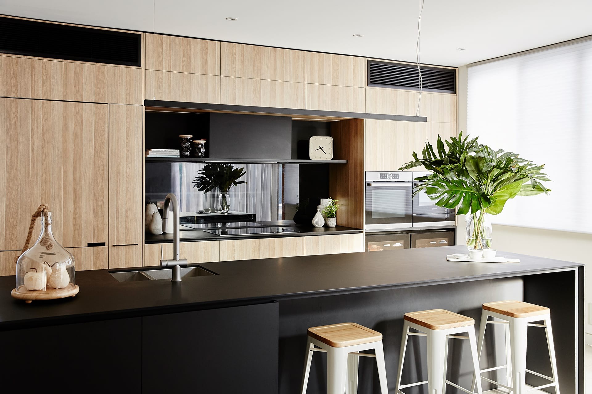 black kitchen with oak cabinetry and tinted mirror splashback property styling melbourne