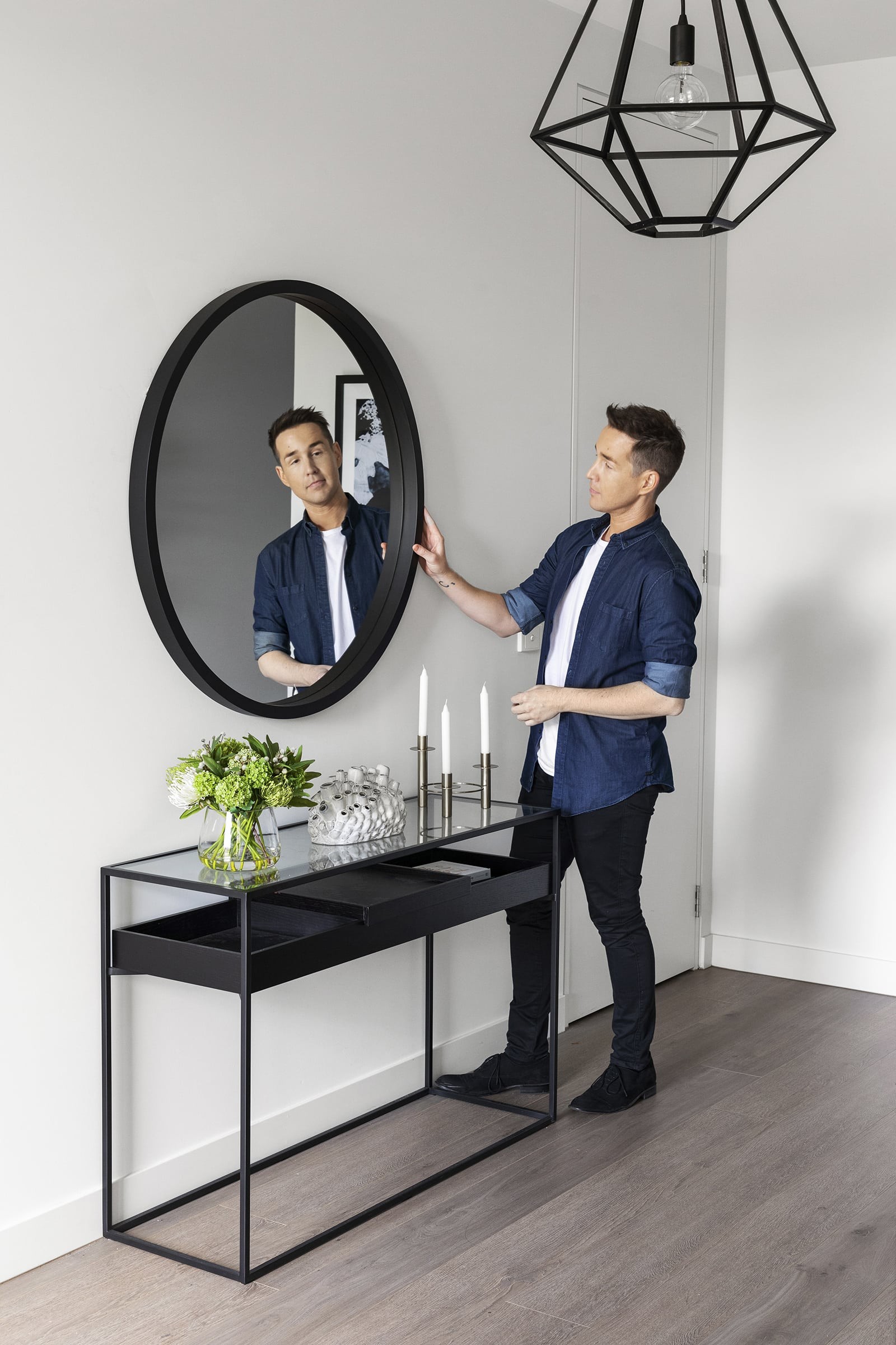 black round mirror in entryway above black and glass top console table from calibre furniture