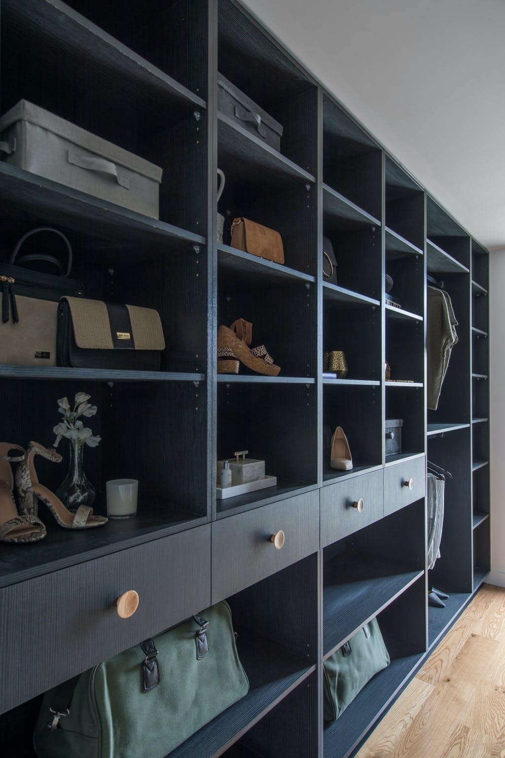 black walk in robe cabinetry with round oak handles and open cube shelving
