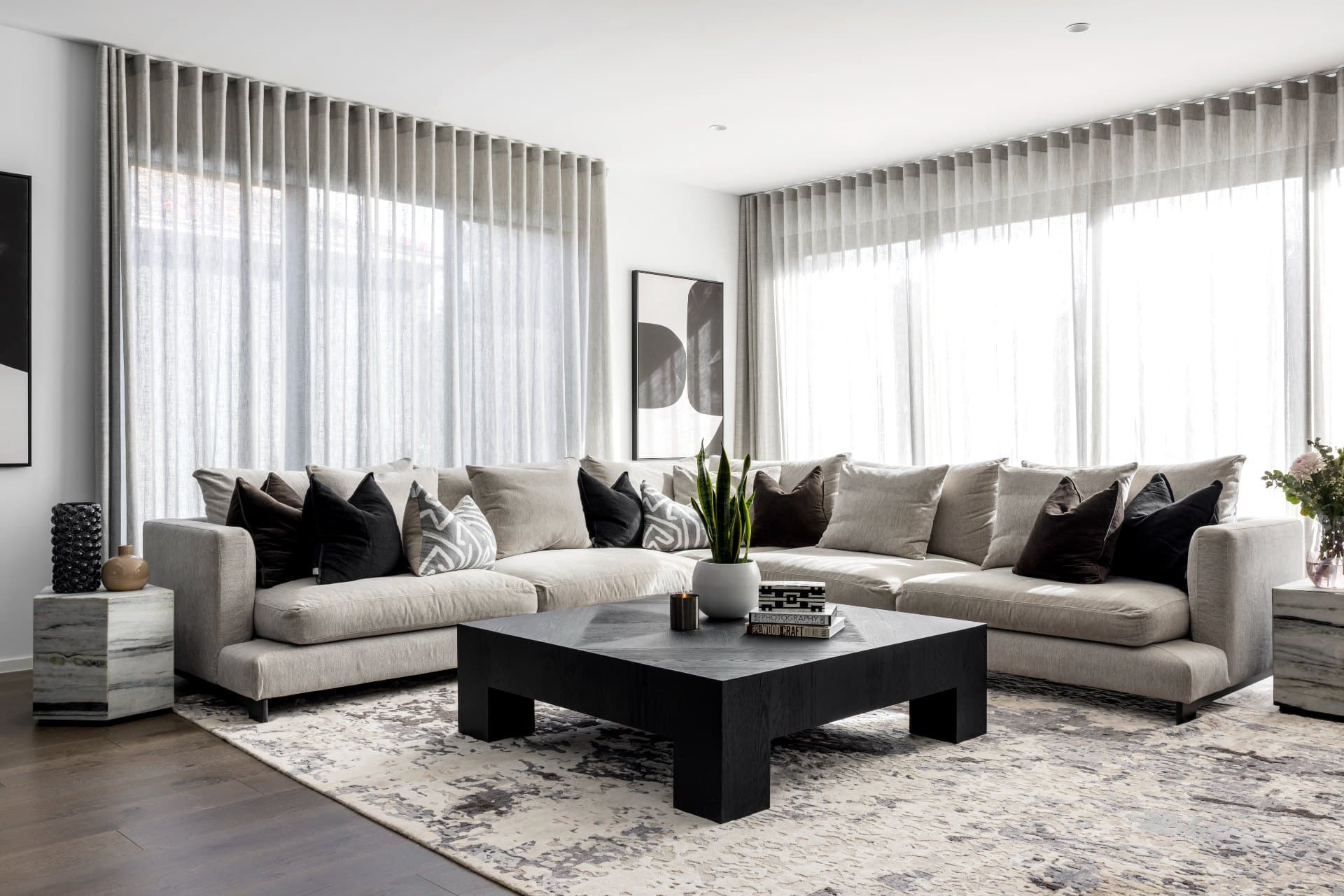 black white and grey contemporary luxe living room with grey sheer curtains grey sectional sofa and timber coffee table