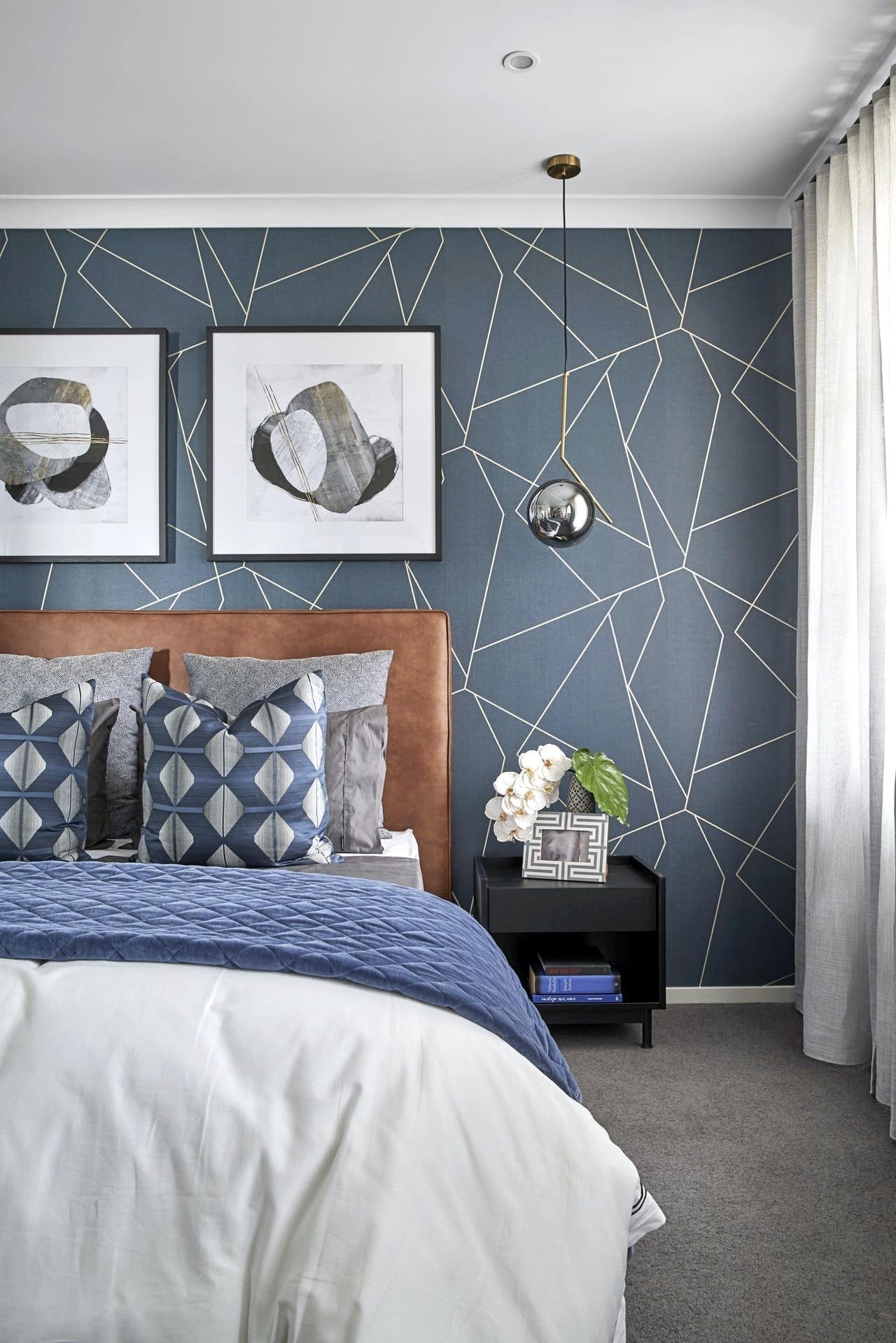 blue and white geometric wallpaper in bedroom with tan leather bedhead and blue bedding