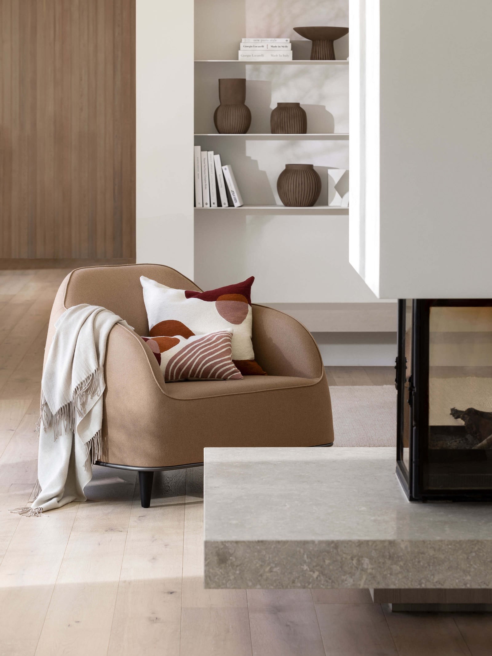 brown suede armchair with beige throw blanket in living room with concrete fireplace