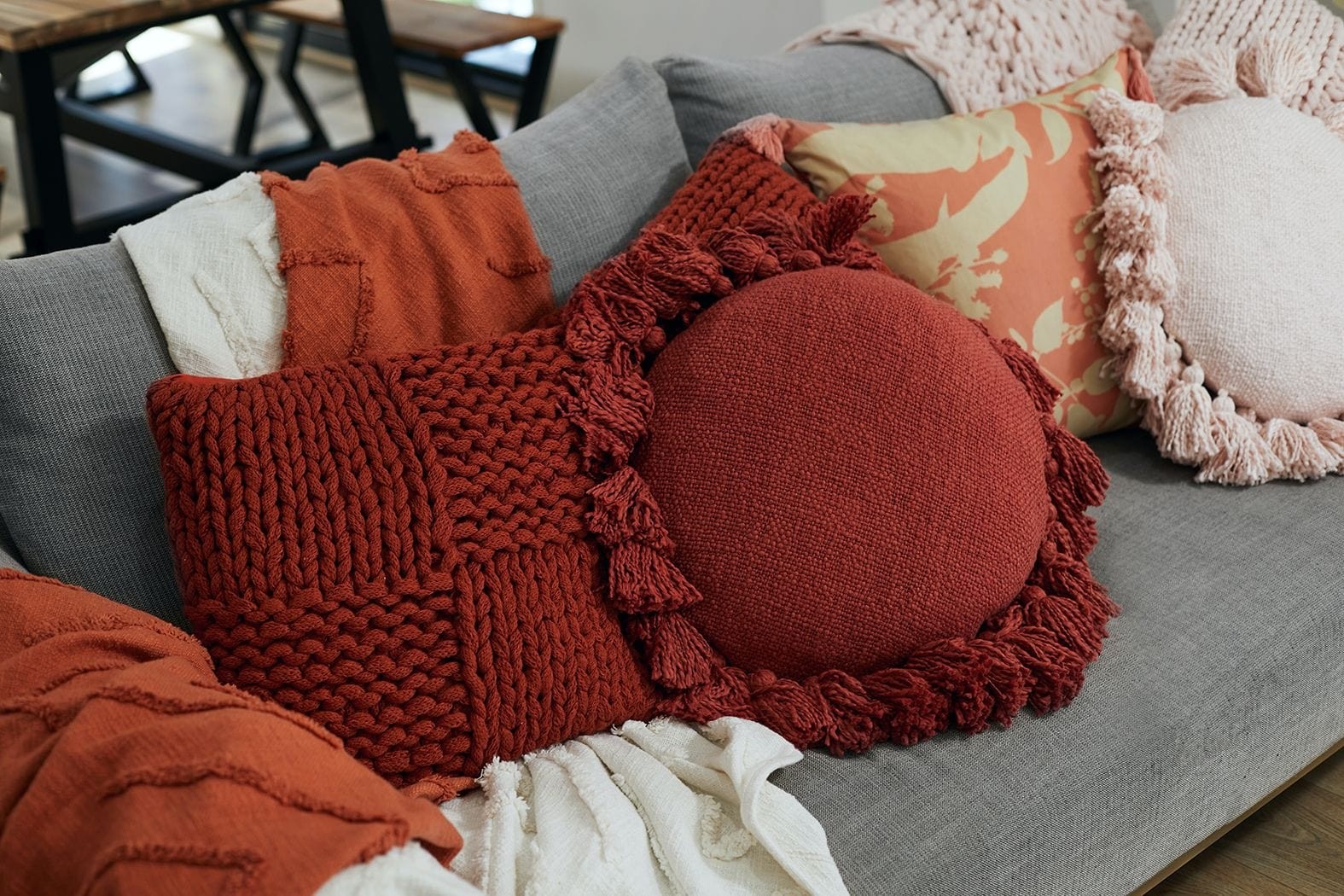 burnt orange and terracotta cushions and throws on grey sofa from lorraine lea