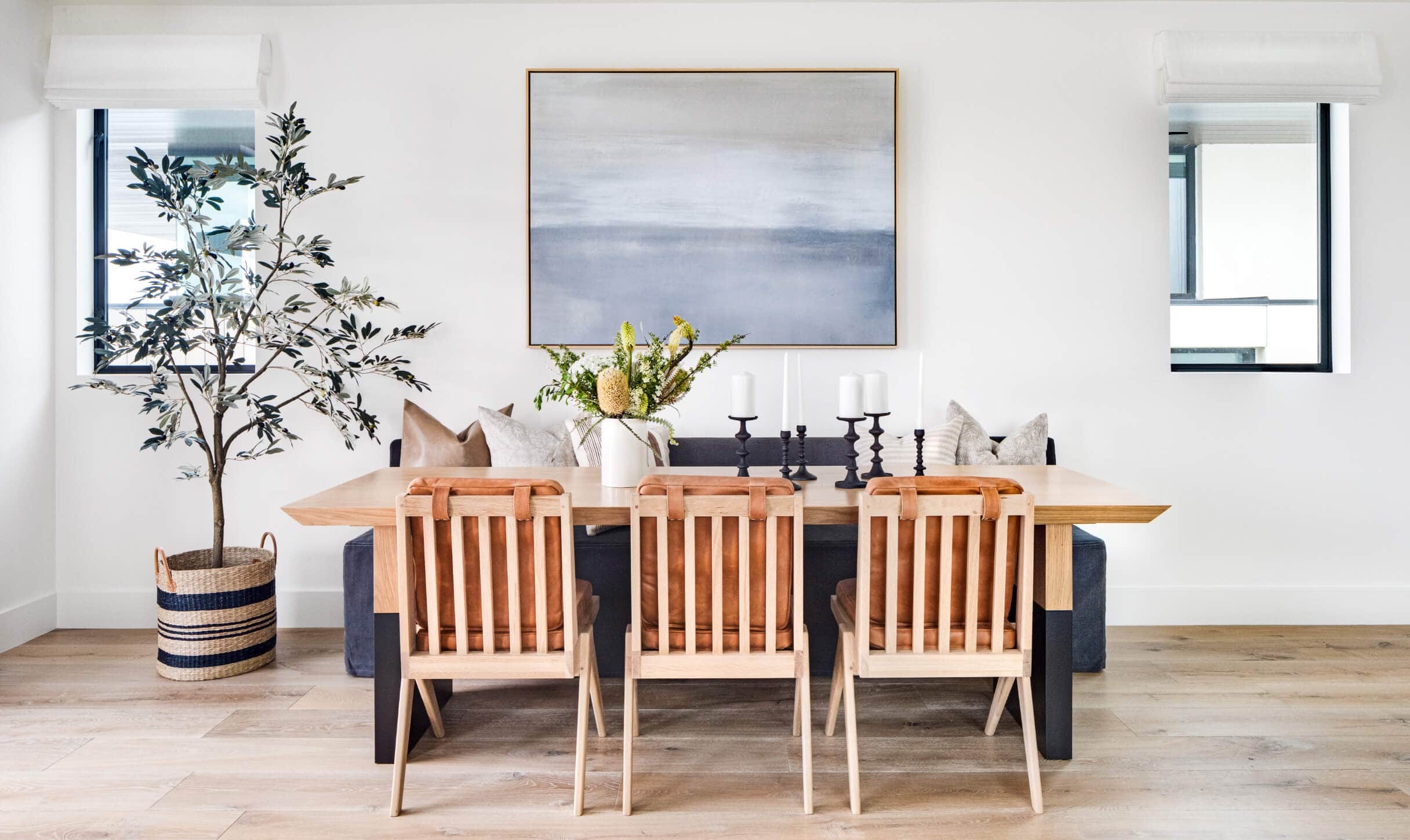 california cool dining room with woven leather dining chairs and large olive tree in rattan basket