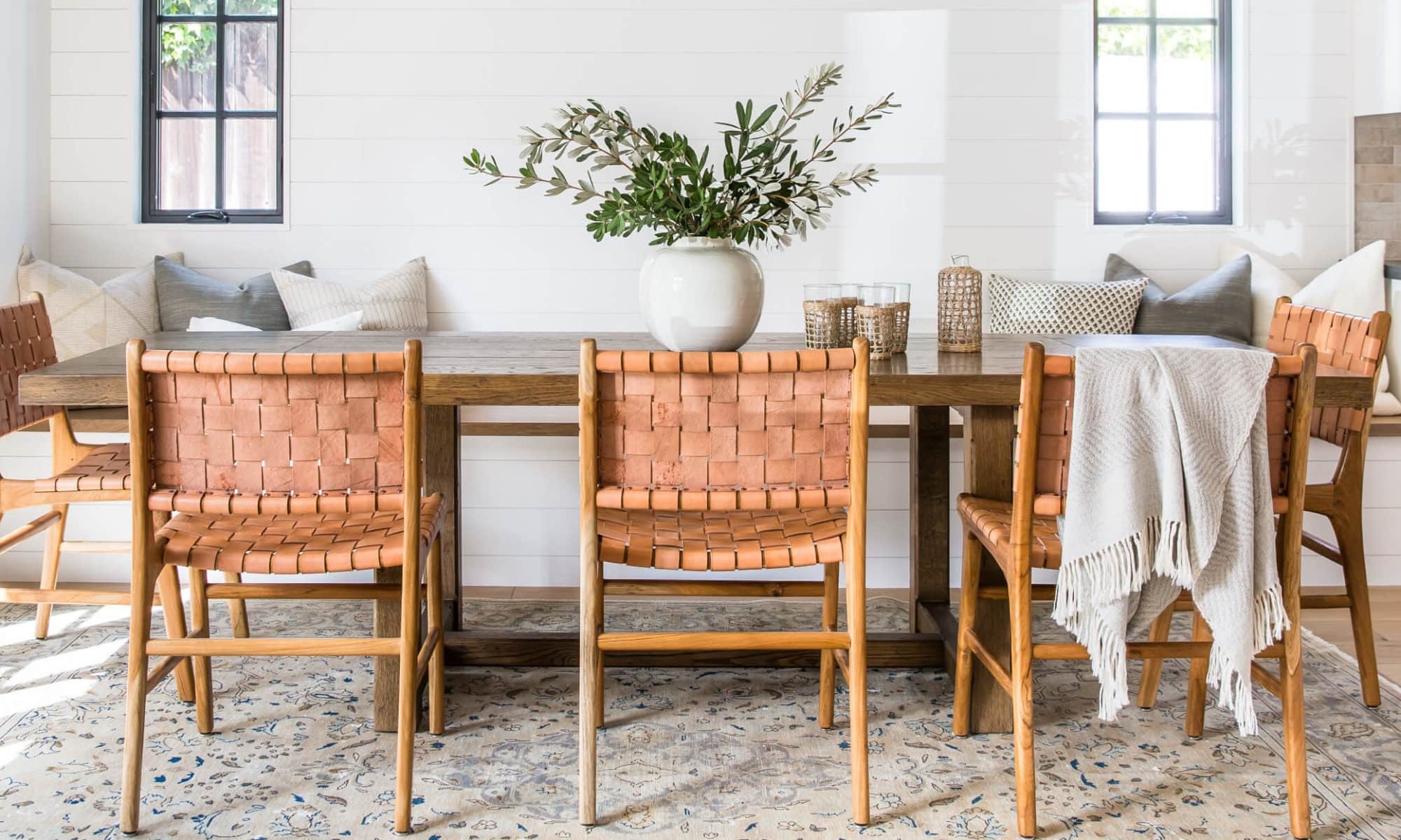 california cool interior design dining room with woven leather dining chairs and rustic table