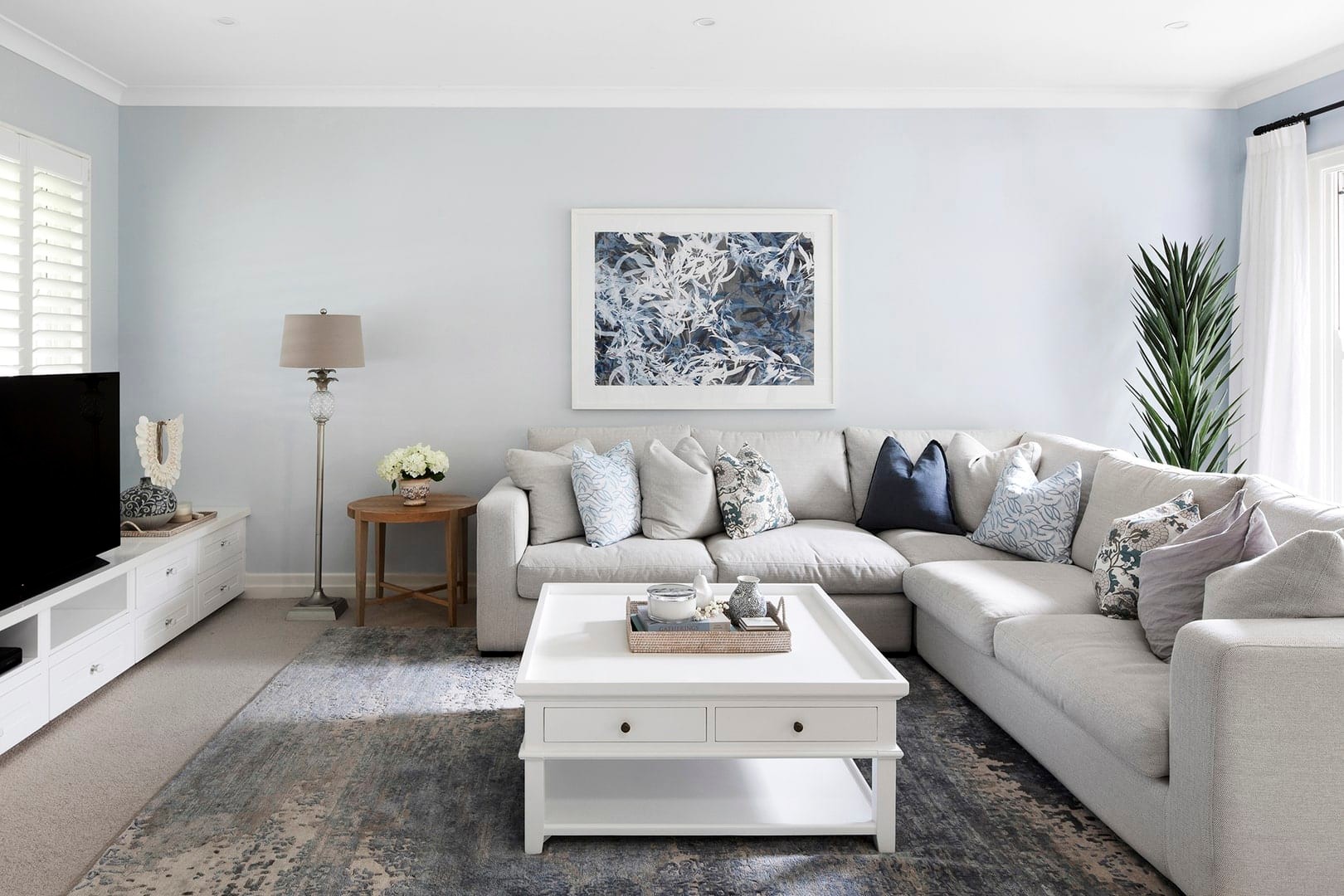 classic hamptons interior design scheme living room with light blue walls and cream sectional sofa