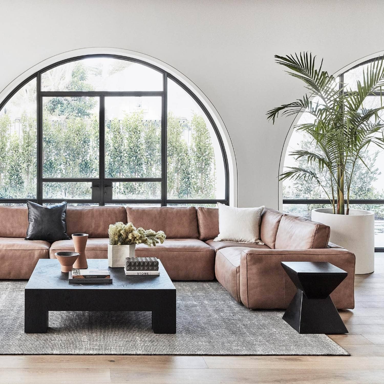 coco republic living room with brown leather sofa and black floor rug