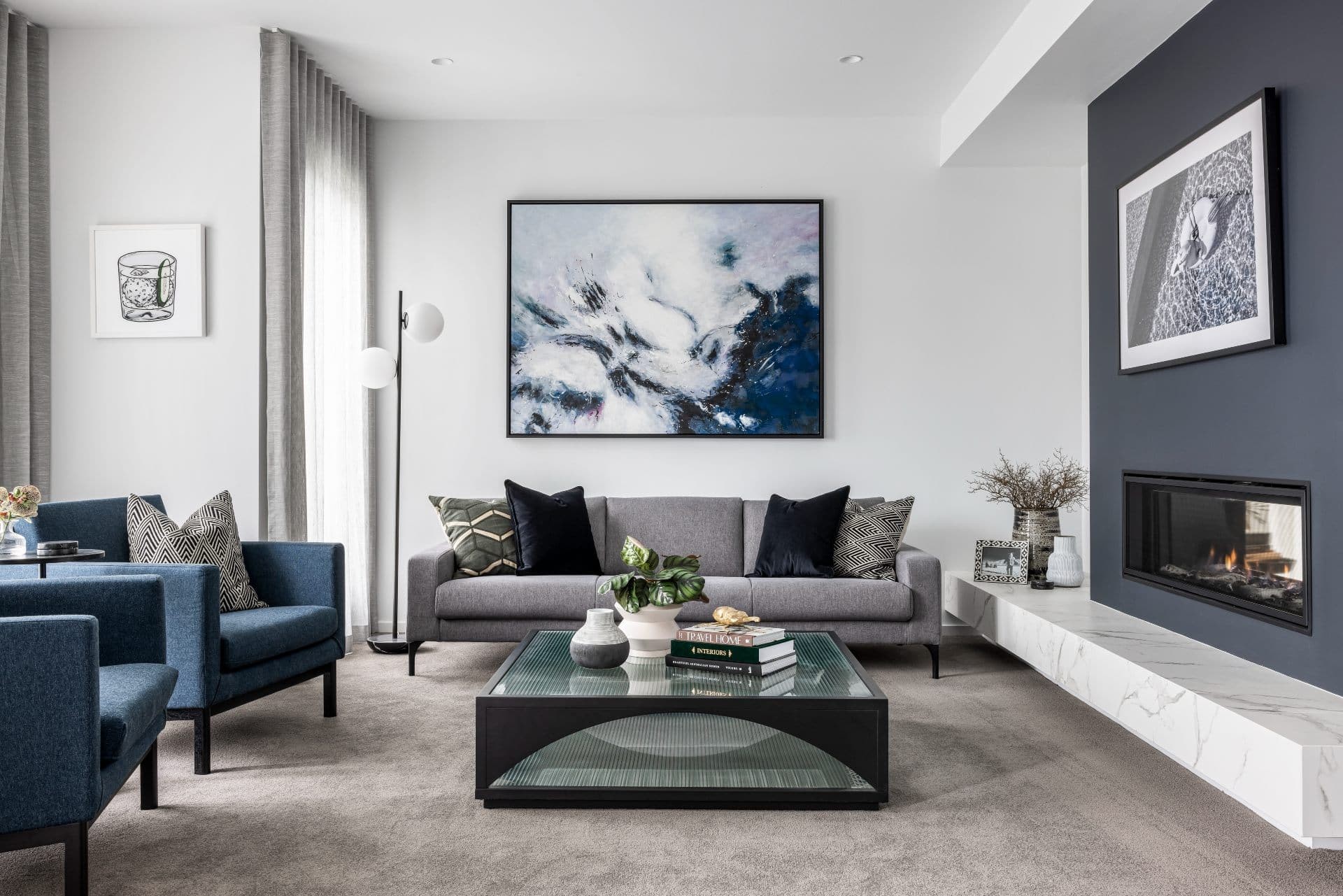 contemporary luxe formal living room with grey sofa navy blue armchairs abstract artwork and dark blue fireplace feature wall