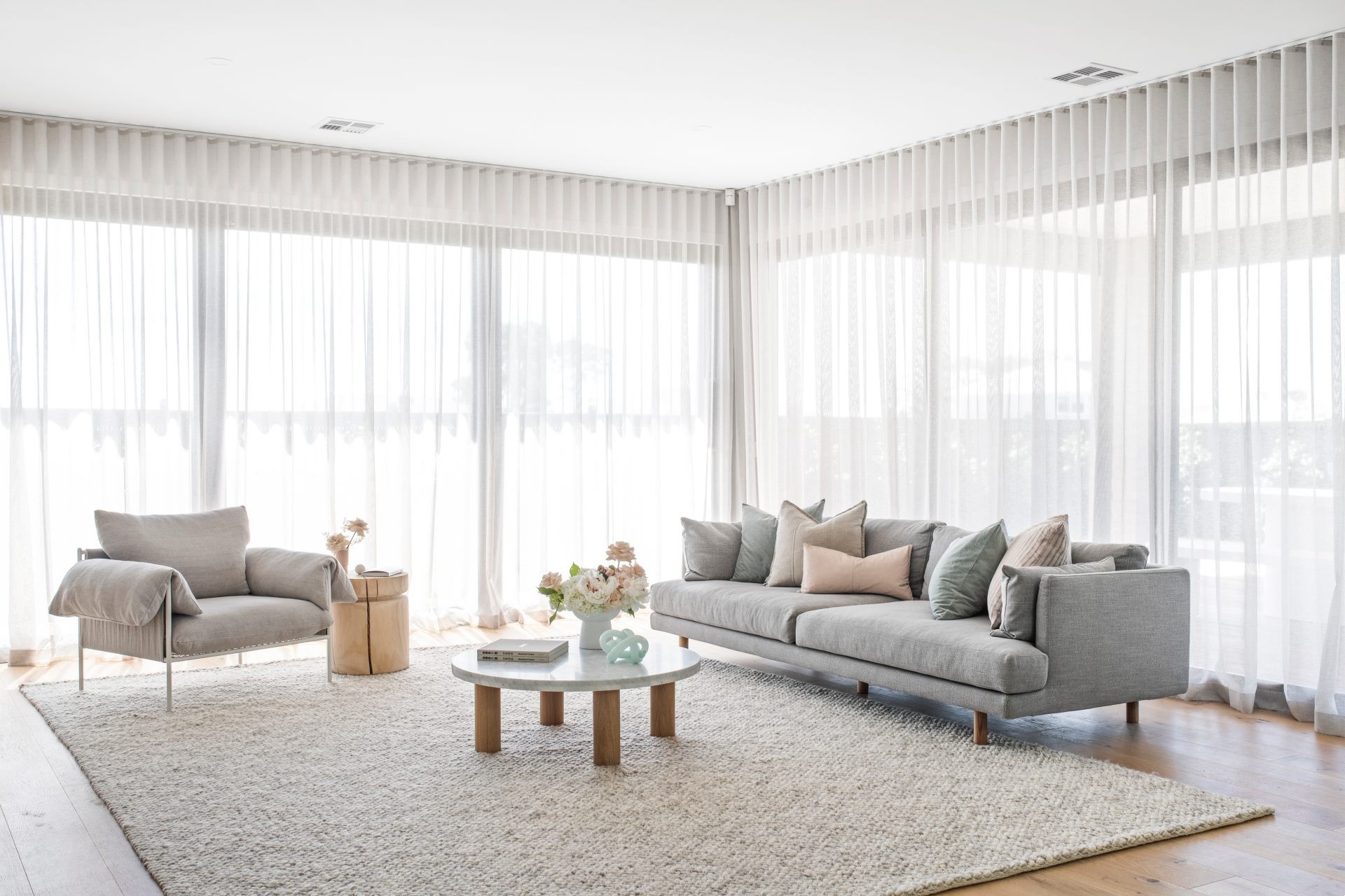 contemporary white living room with white s fold sheer curtains and modern grey sofa beige rug