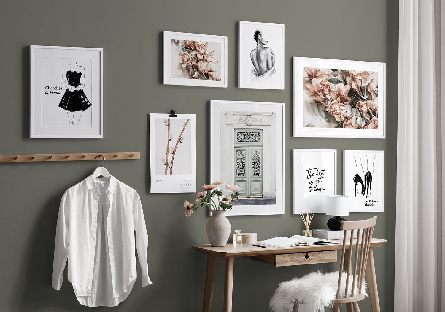 creating a gallery wall of art in white frames on olive green wall