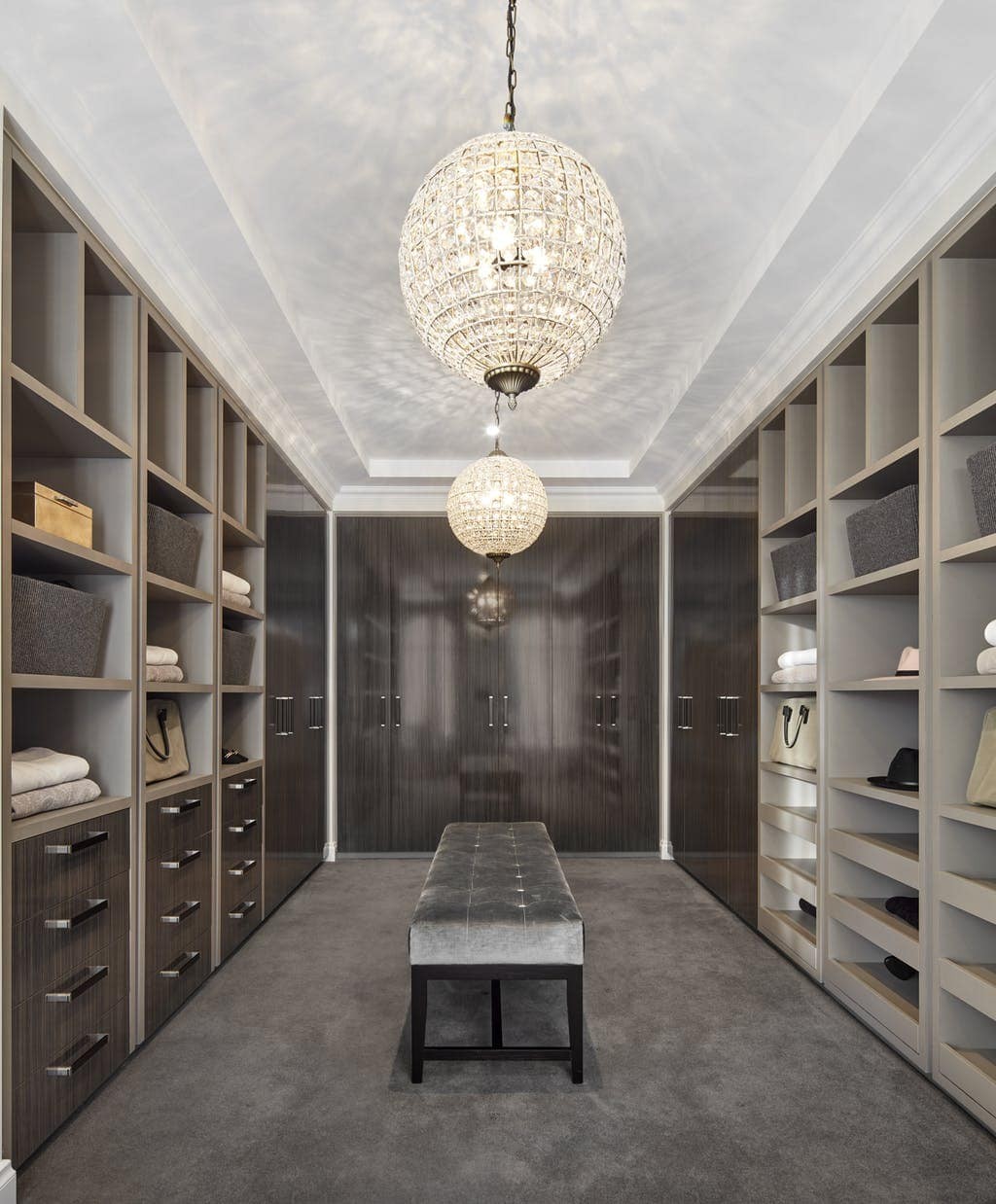 dark timber walk in closet with large pendant lights and velvet bench seat