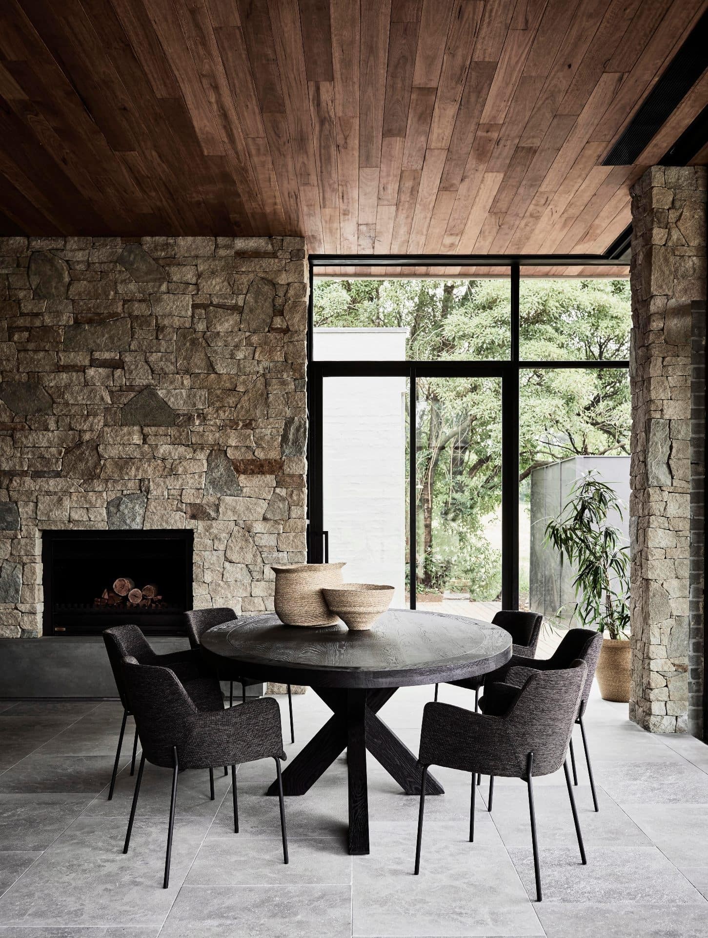 globewest round dark timber dining table with upholstered chairs in dining room with grey concrete tiles
