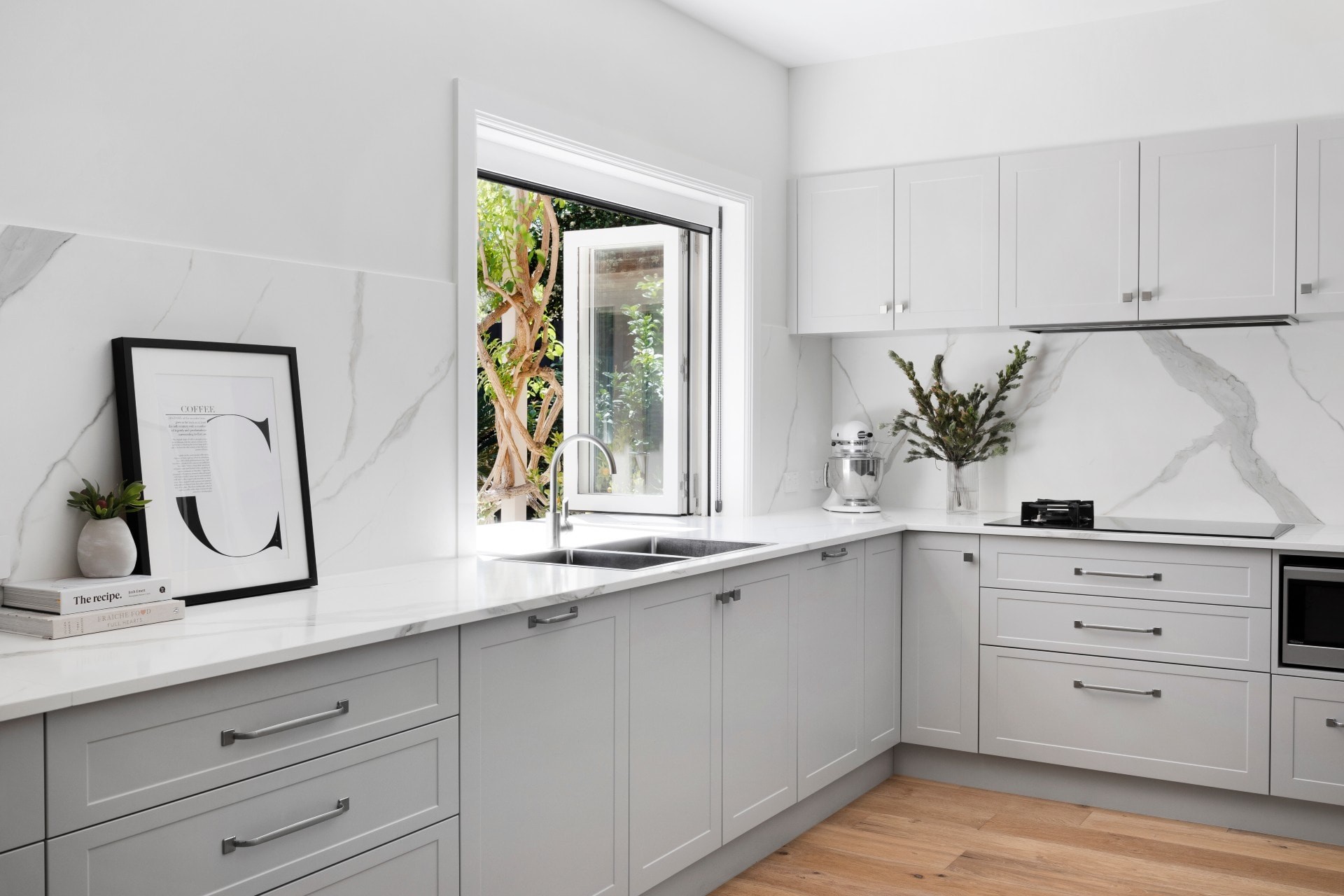 grey and white shaker style hamptons kitchen with oak flooring white stone splashback and servery window