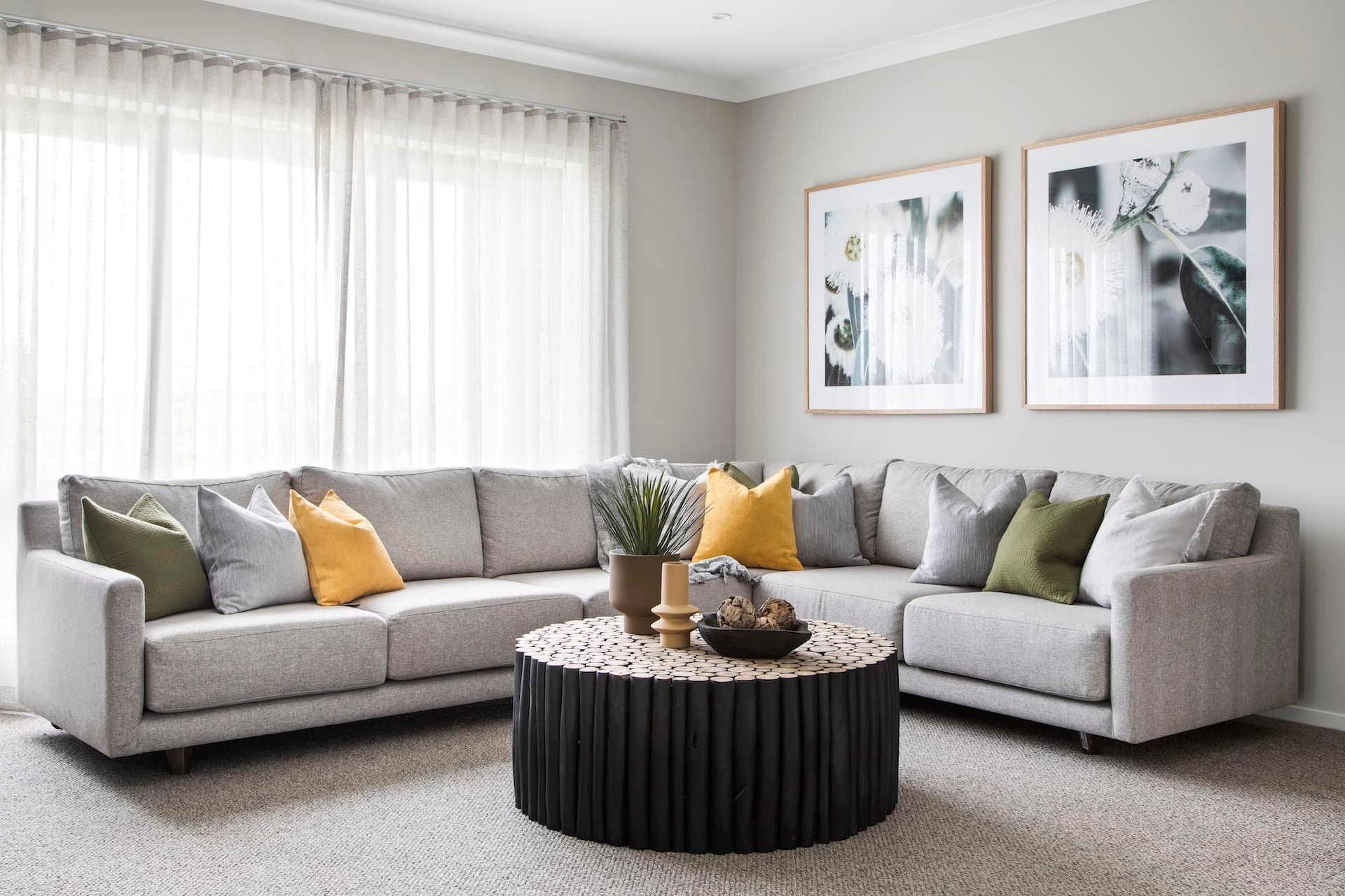 grey sectional sofa with round black timber table and green and yellow cushions