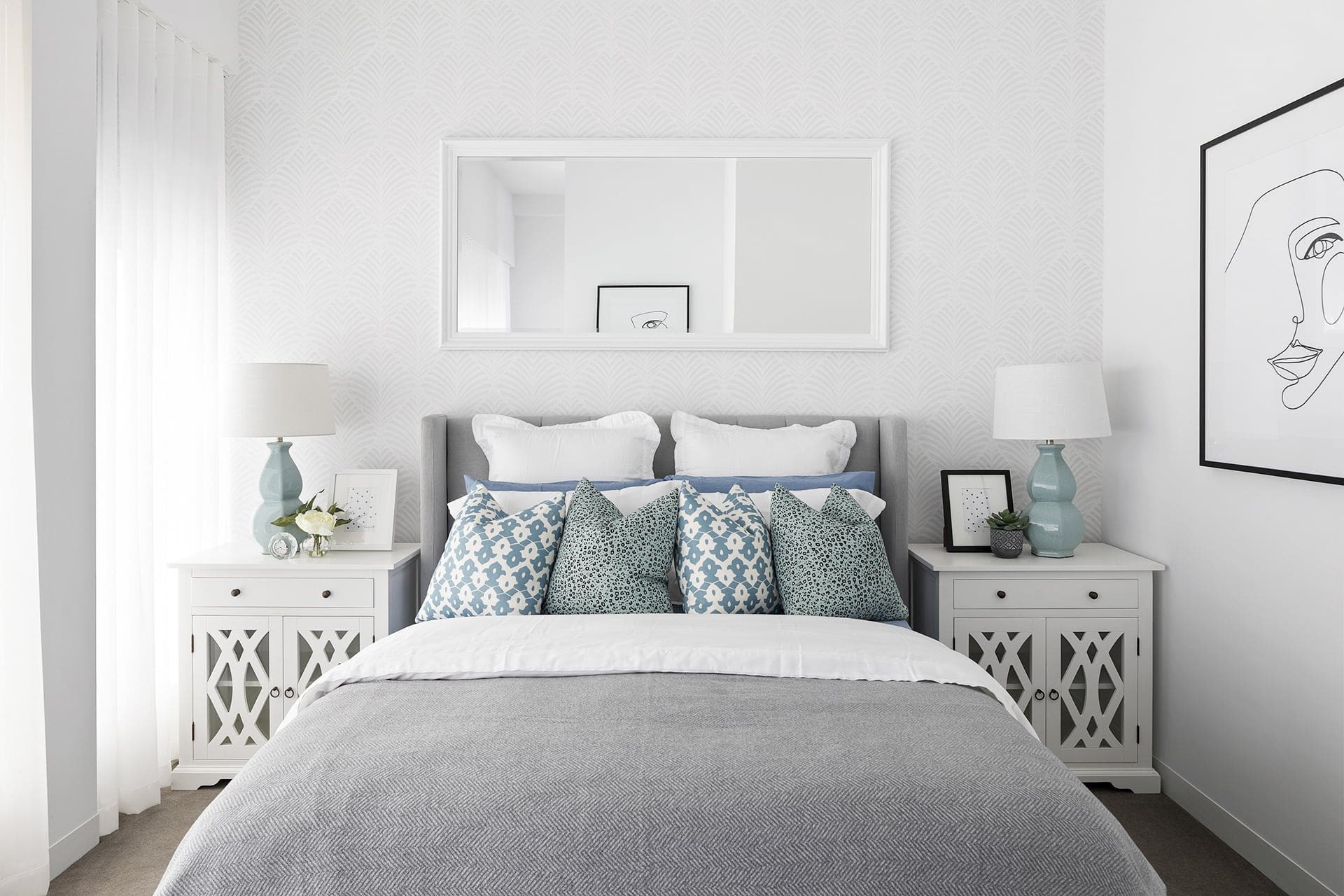hamptons style master bedroom with white bedside tables and mirror above bed