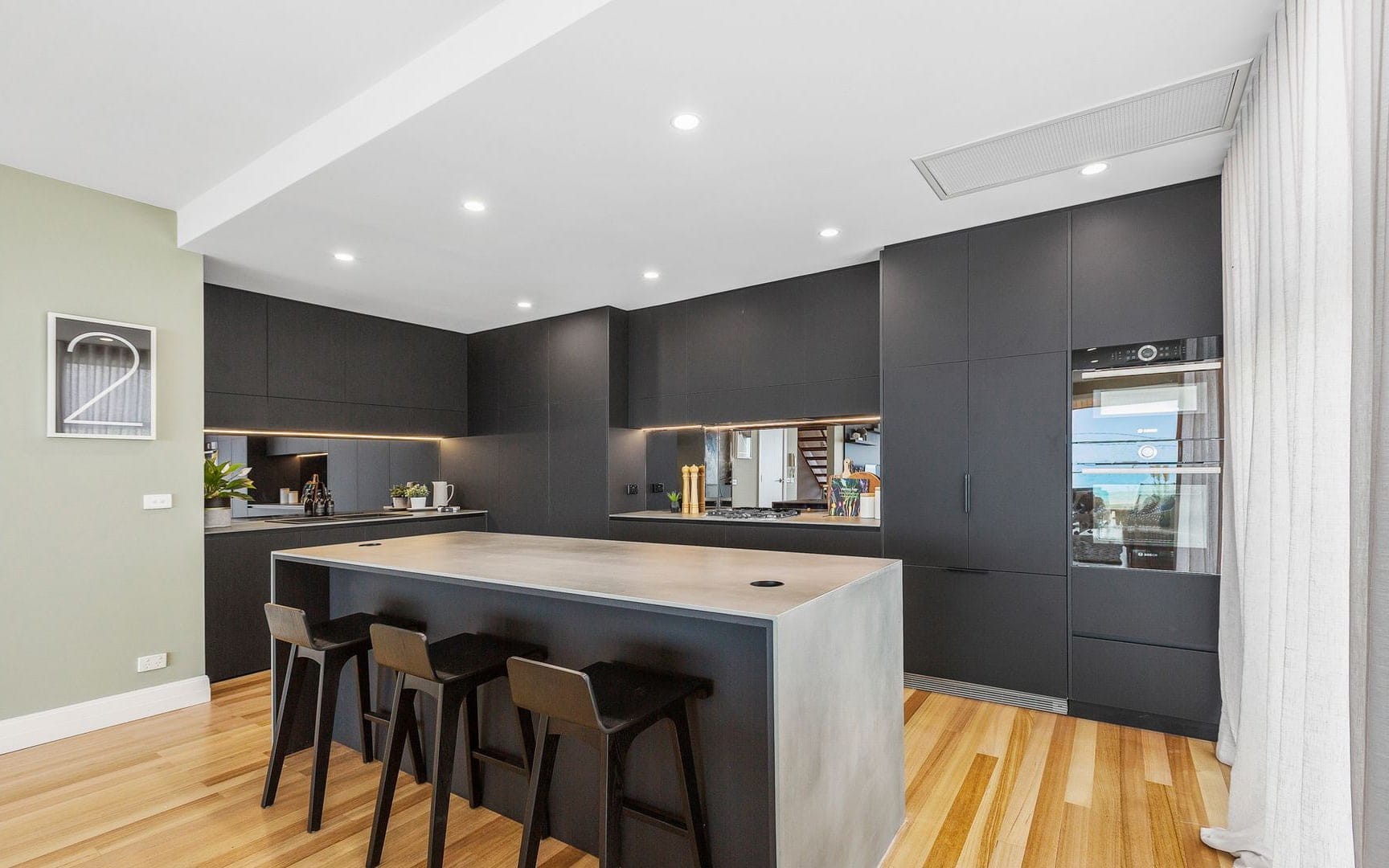 industrial kitchen design with black laminex cabinetry grey stone countertops and tinted glass splashback