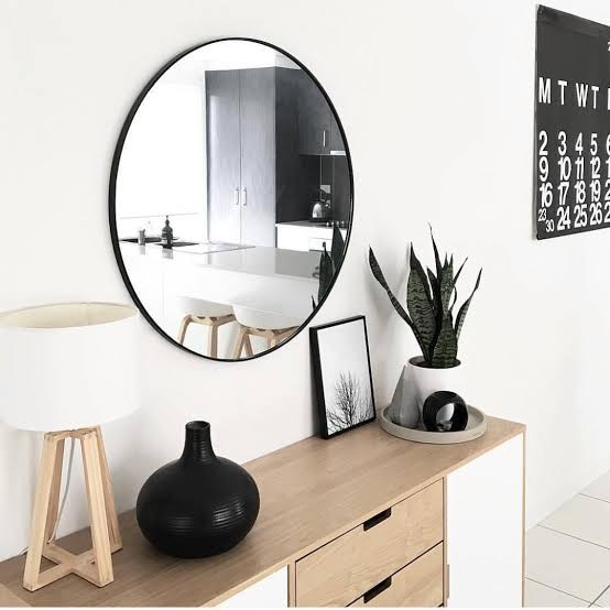 kmart large round mirror with black frame hanging above timber sideboard