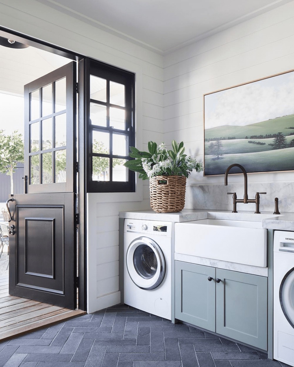 laundry room with landscape artwork on wall and black external farmhouse door