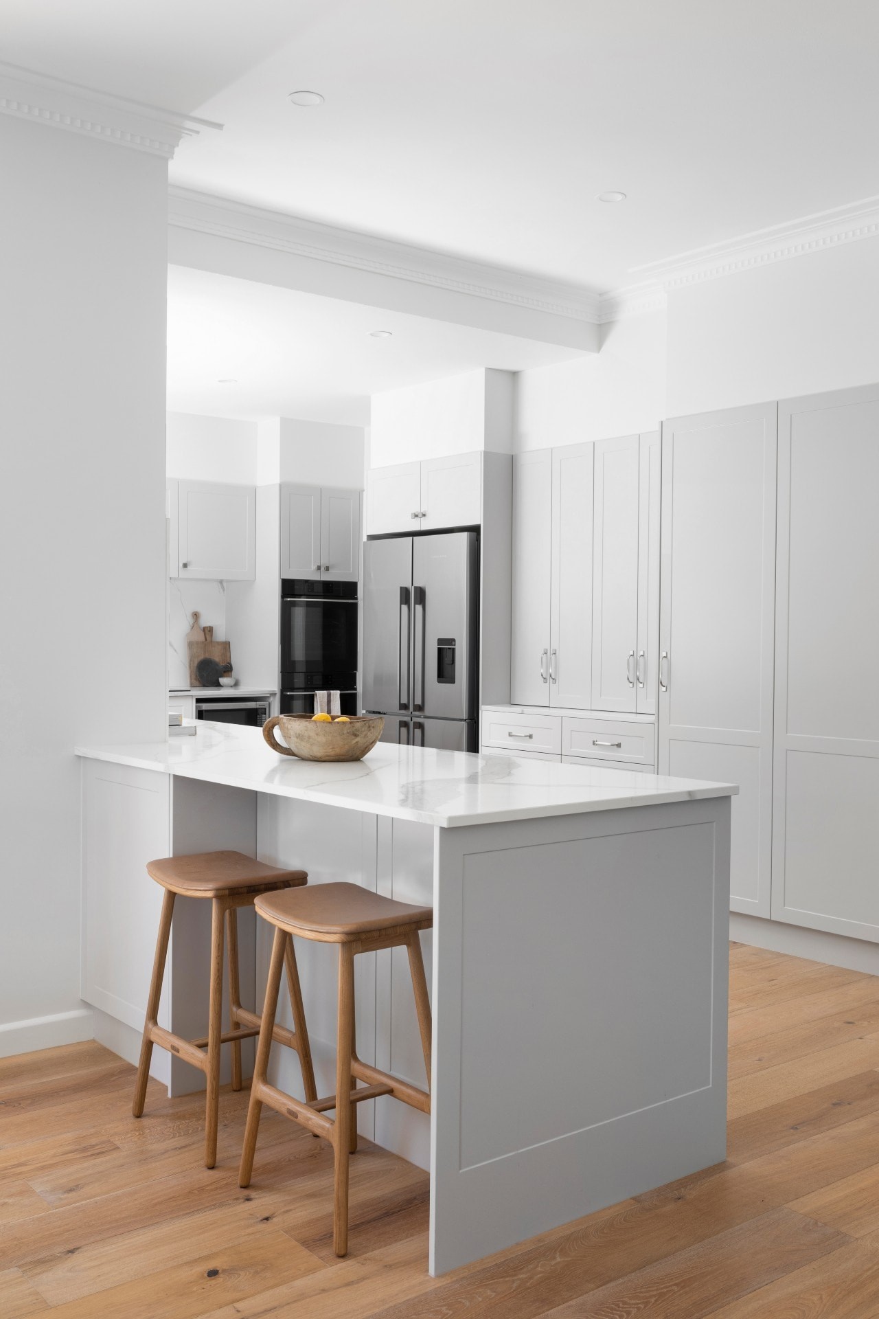 light grey shaker style kitchen with oak flooring and white countertop