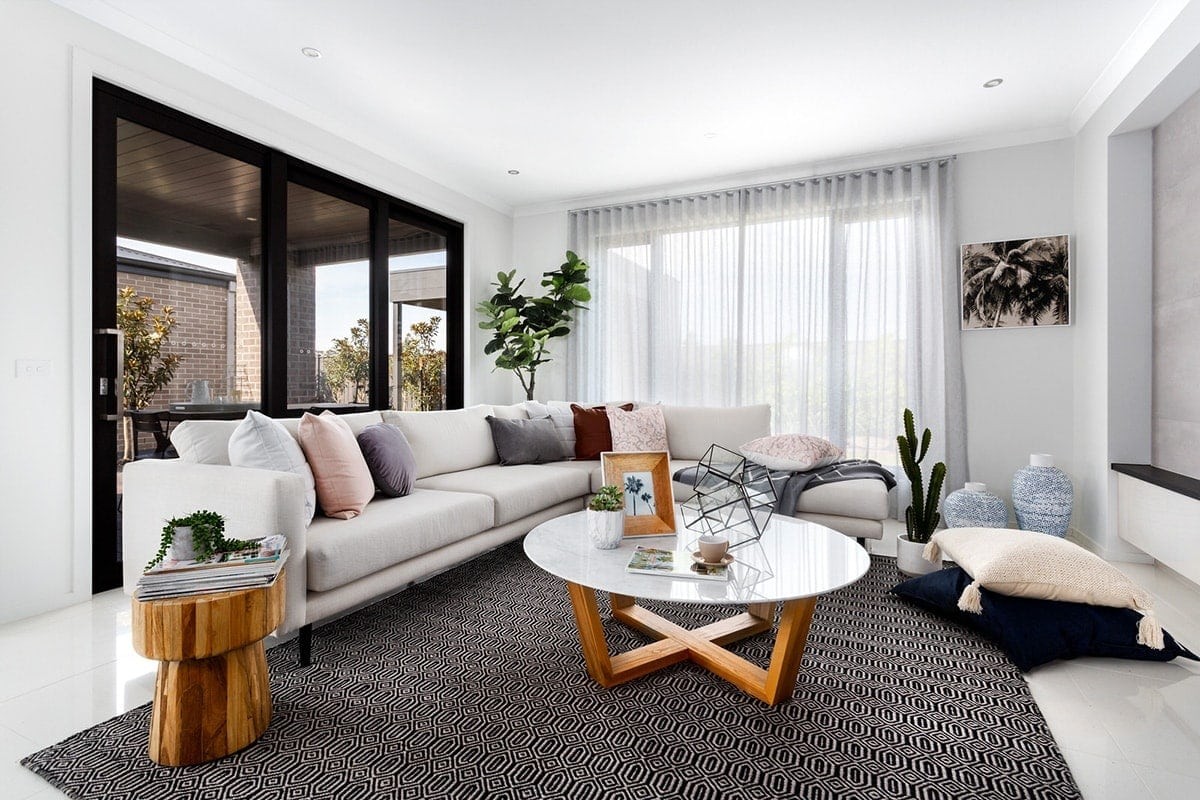 living room with white sofa and pink and maroon cushions from metricon display home