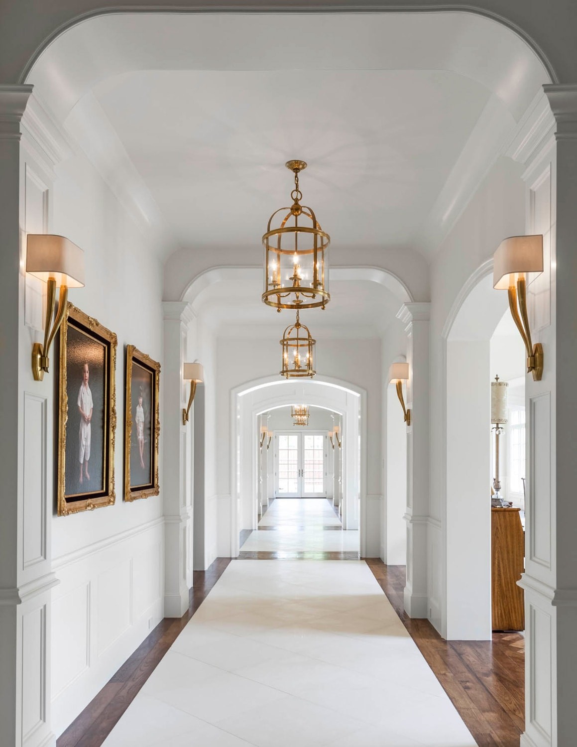 long white hallway with brass pendant lights and tiled floor