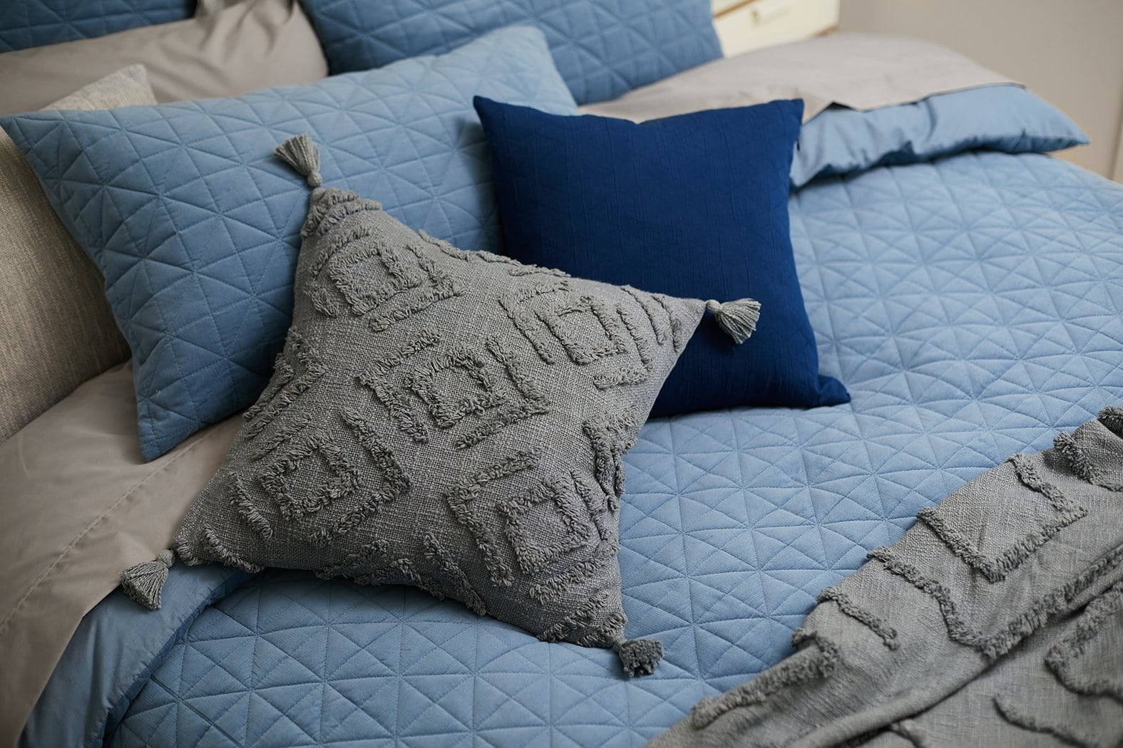 lorraine lea blue quilted bedding set with grey cushion and throw blanket