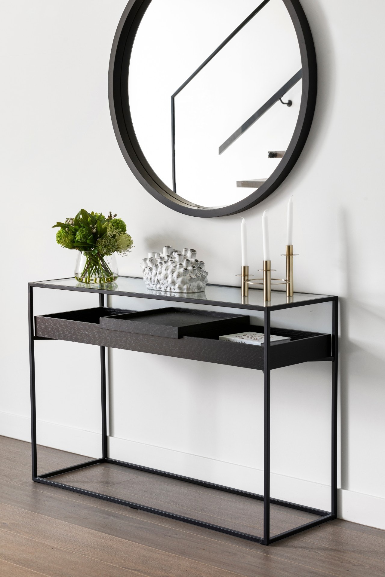 minimalist entryway with black console table and round black mirror