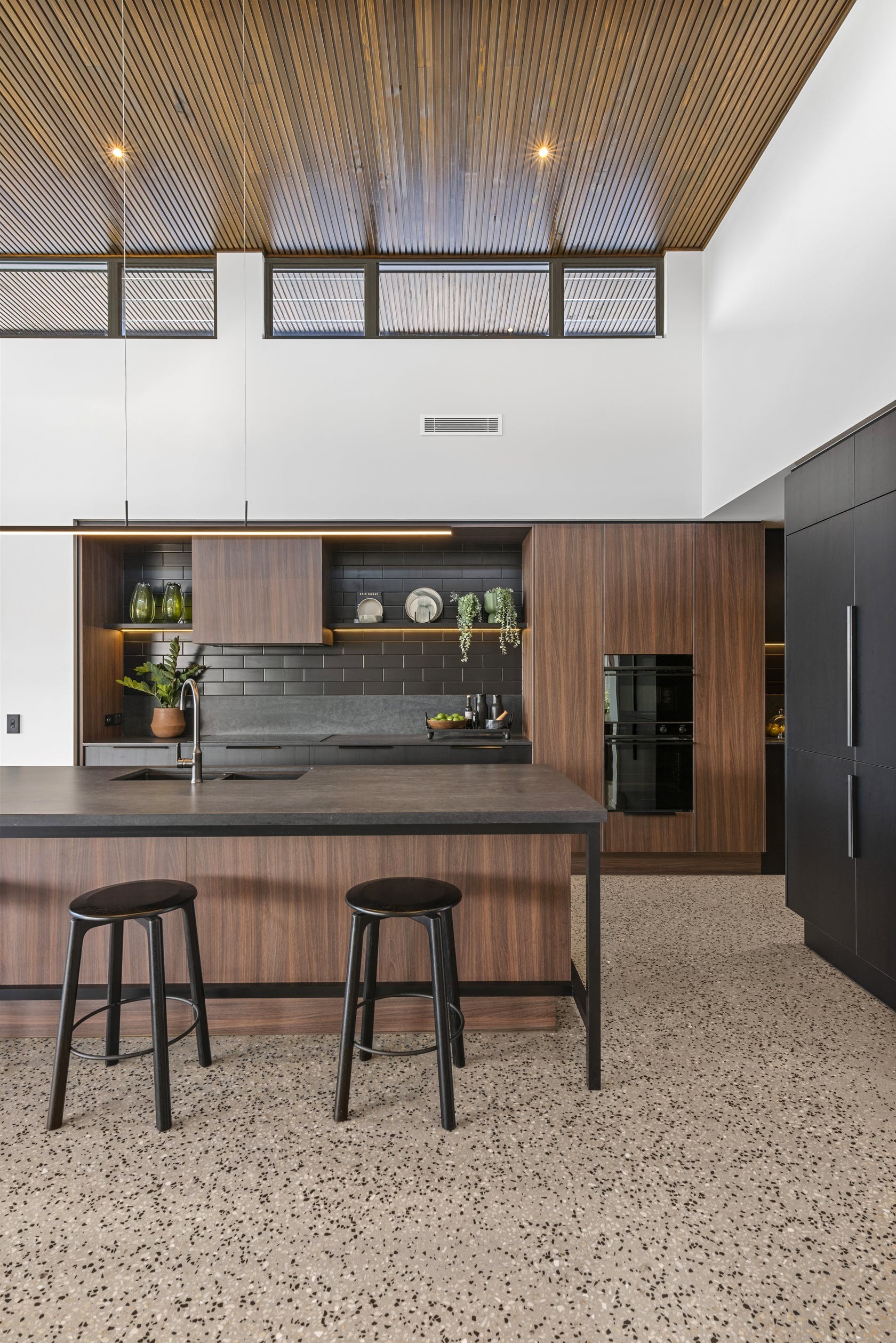 modern dark brown timber kitchen cabinets and black strip light over kitchen island