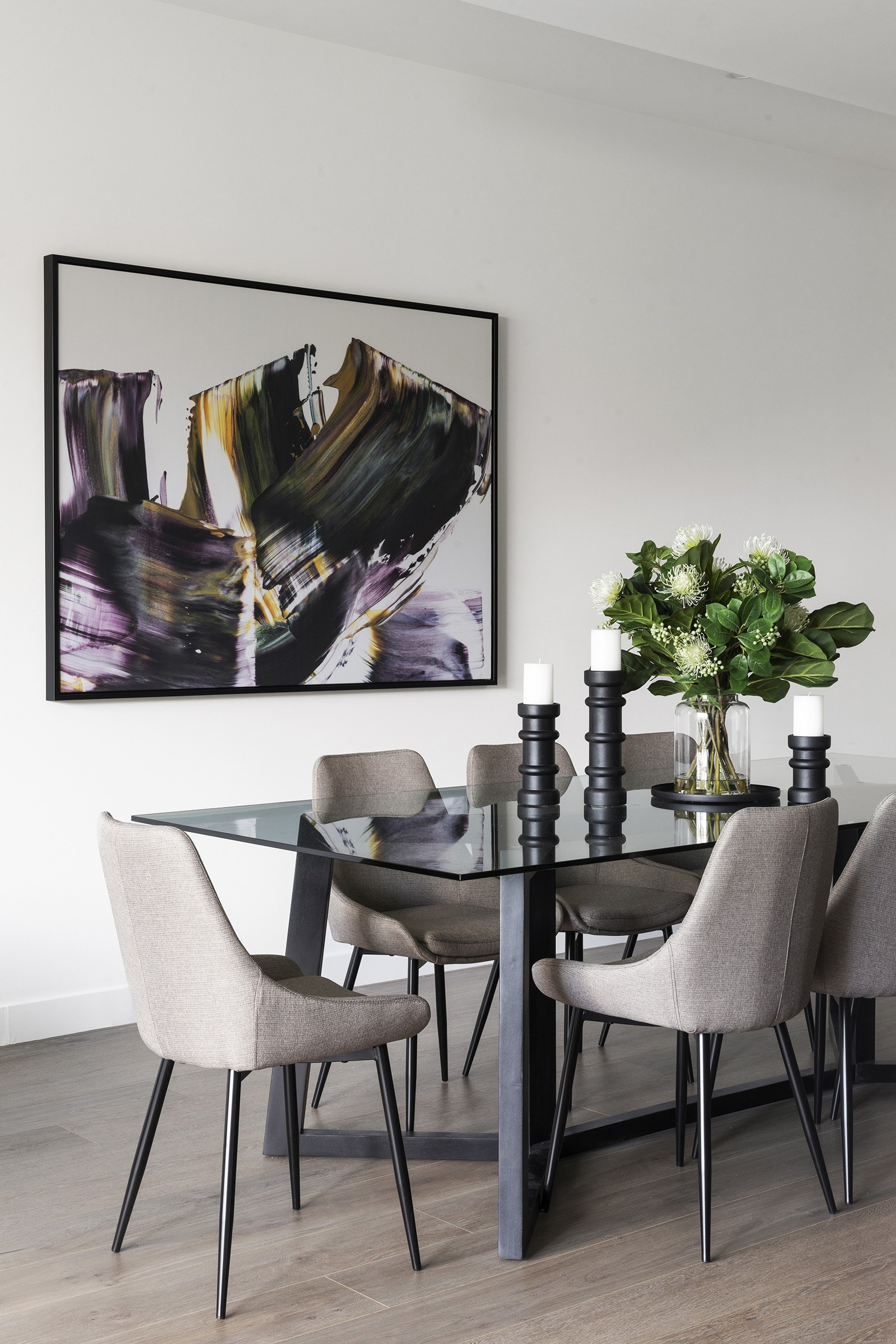 modern luxe dining room with glass top table grey upholstered chairs and fake flowers urban road wall art