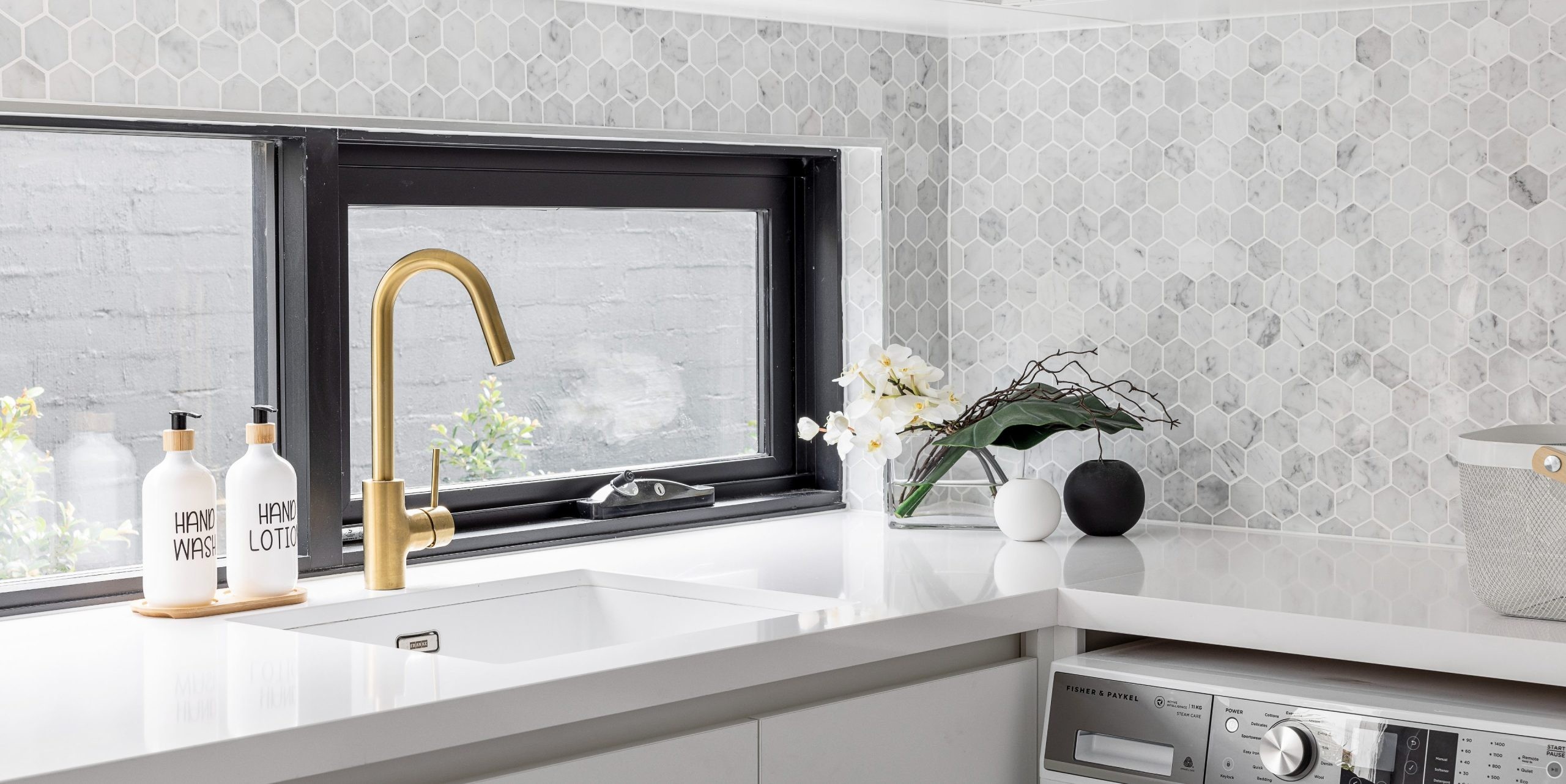 modern white laundry with marble hexagon tiles and brass tap
