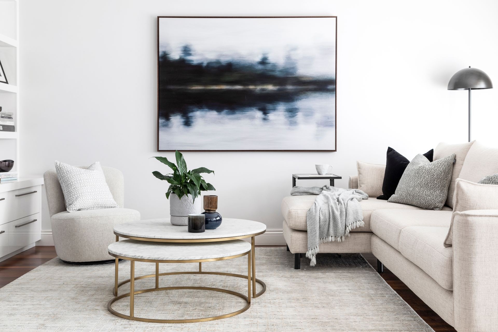 monochromatic living room with moody abstract art from urban road and round marble coffee table