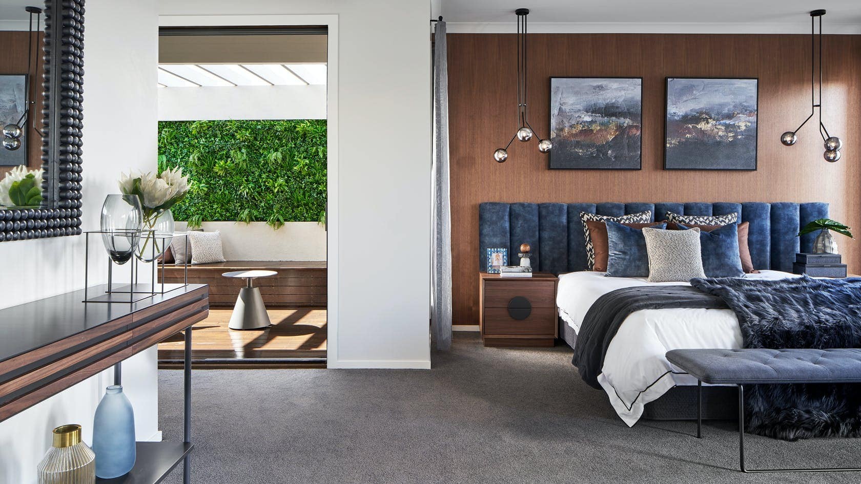 navy blue velvet extra wide headboard in moody luxe master bedroom with brown panel walls