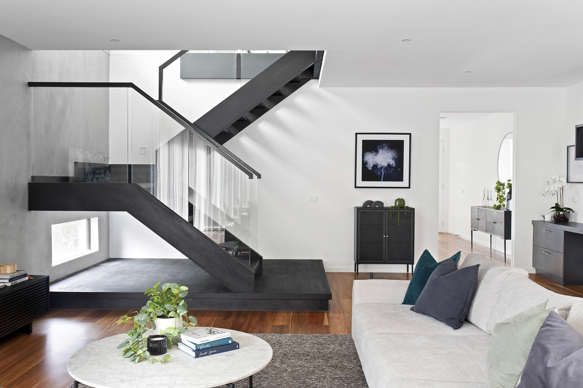 open plan living room with dark staircase glass balistrade and concrete feature wall dulux