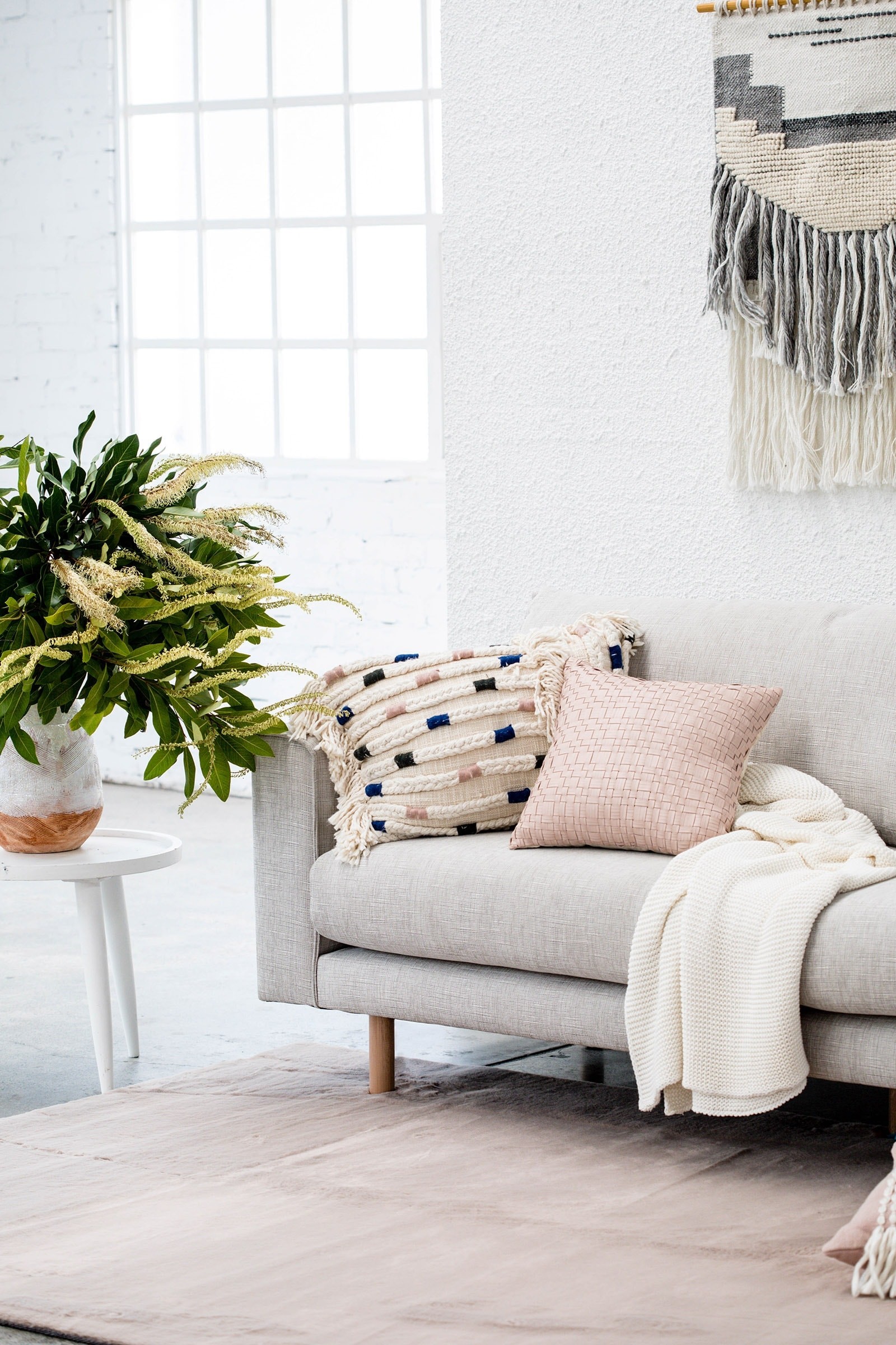 oz design light grey sofa with bohemian cushions and australian natives in vase
