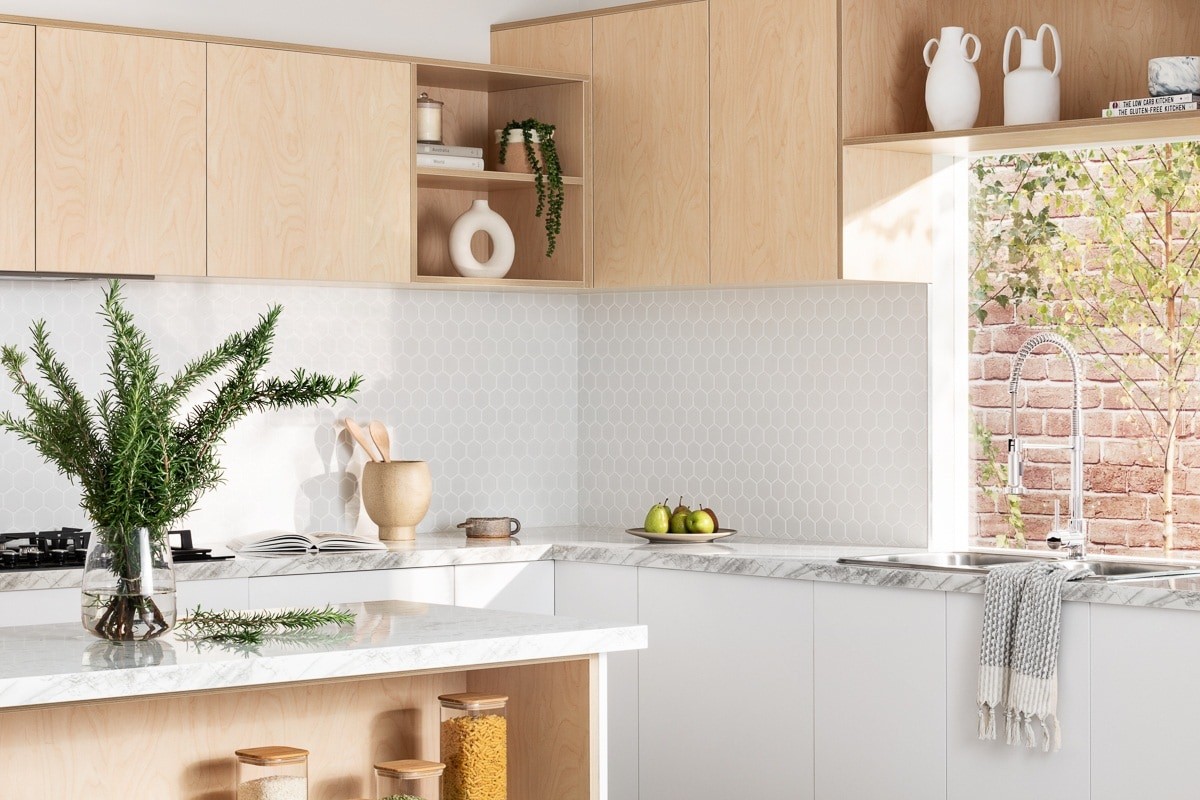 plywood kitchen from kaboodle kitchens with white marble countertops and white hexagon tile splashback