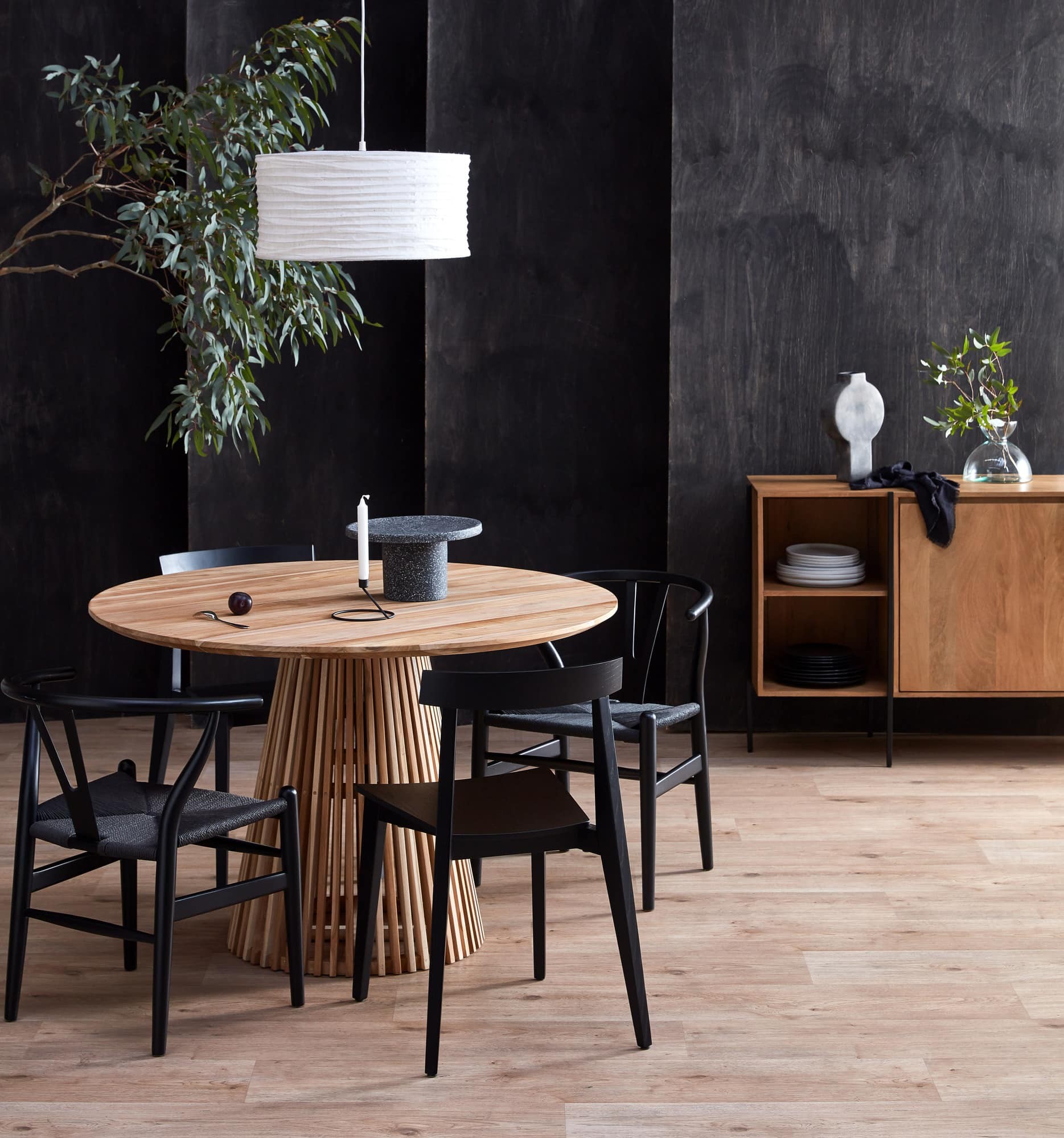 round oak dining table with black dining chairs with woven seat