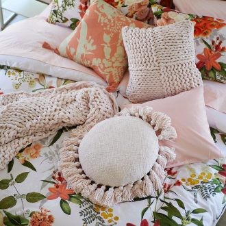 round pink cushion with tassels and pink cable knit throw on floral quilt cover set