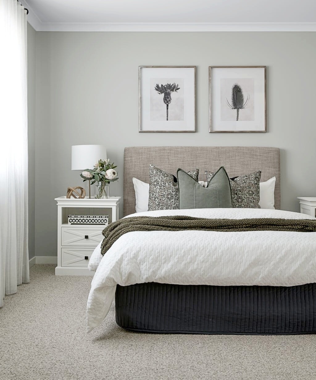 sage green bedroom with two artworks above bed and white hamptons bedside table