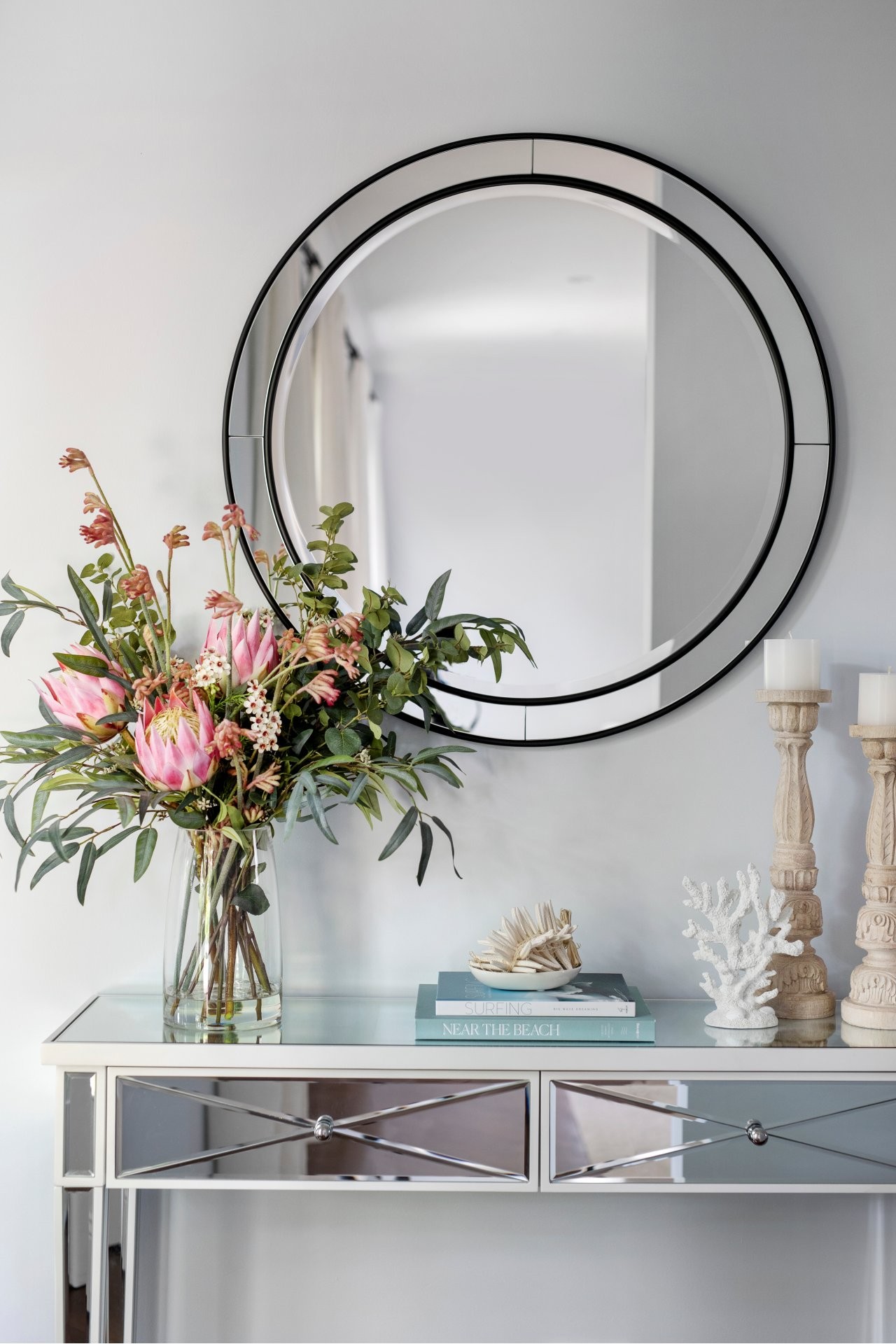 small mirror console table in entry with round mirror and pink flowers in glass vase