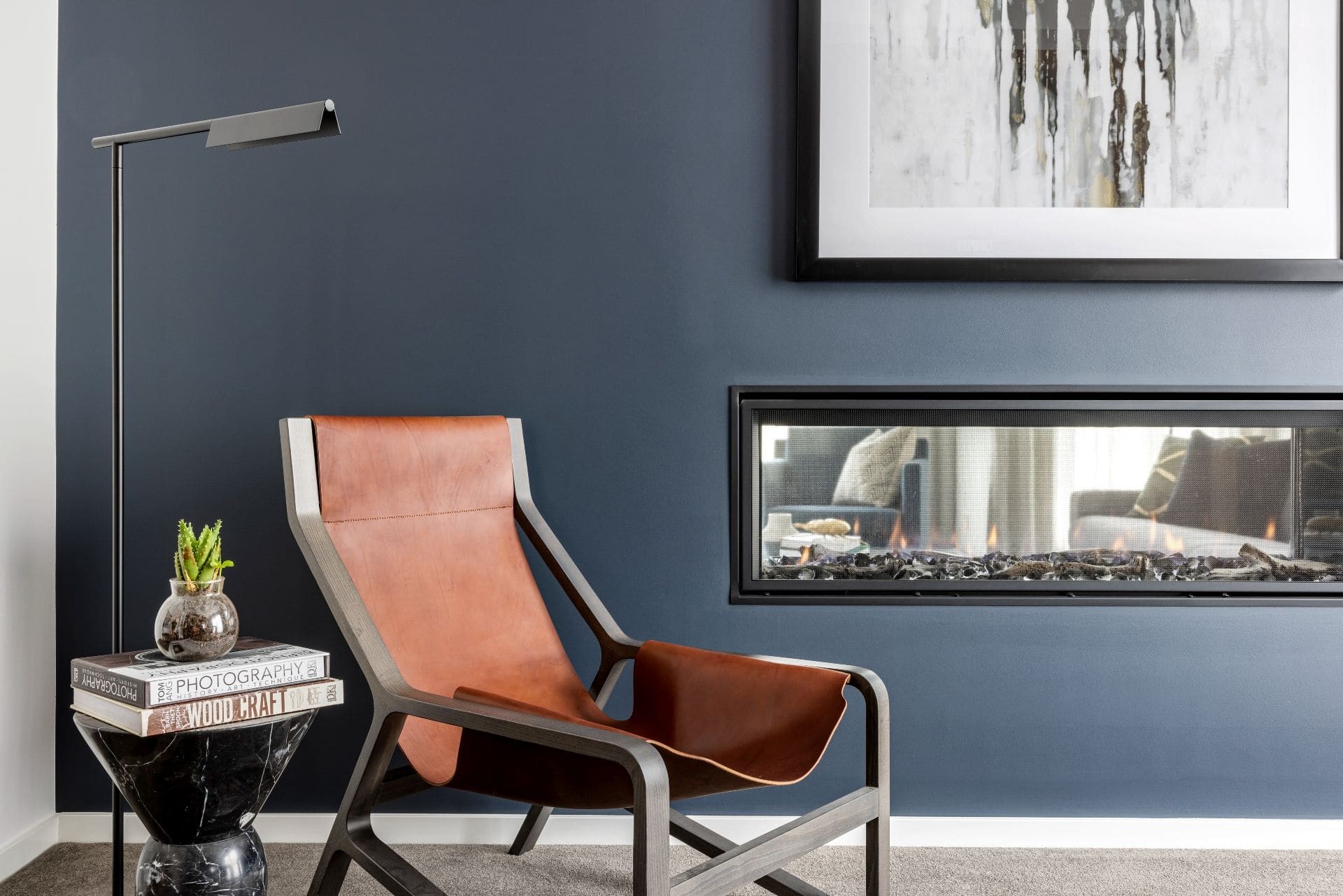 tan leather armchair in room with dark blue grey feature wall and fireplace