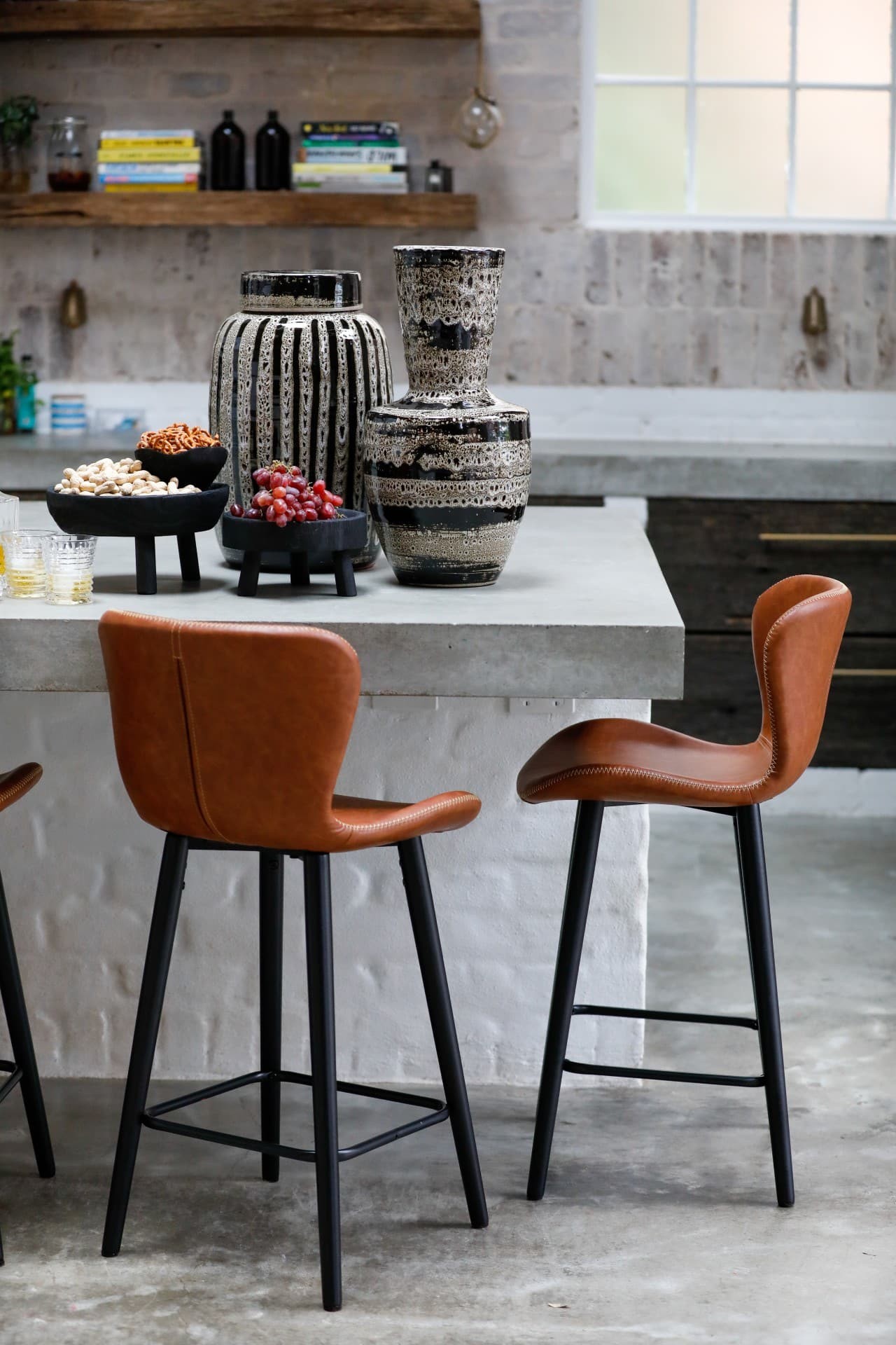 tan leather bench stools in industrial warehouse kitchen with ceramic vases