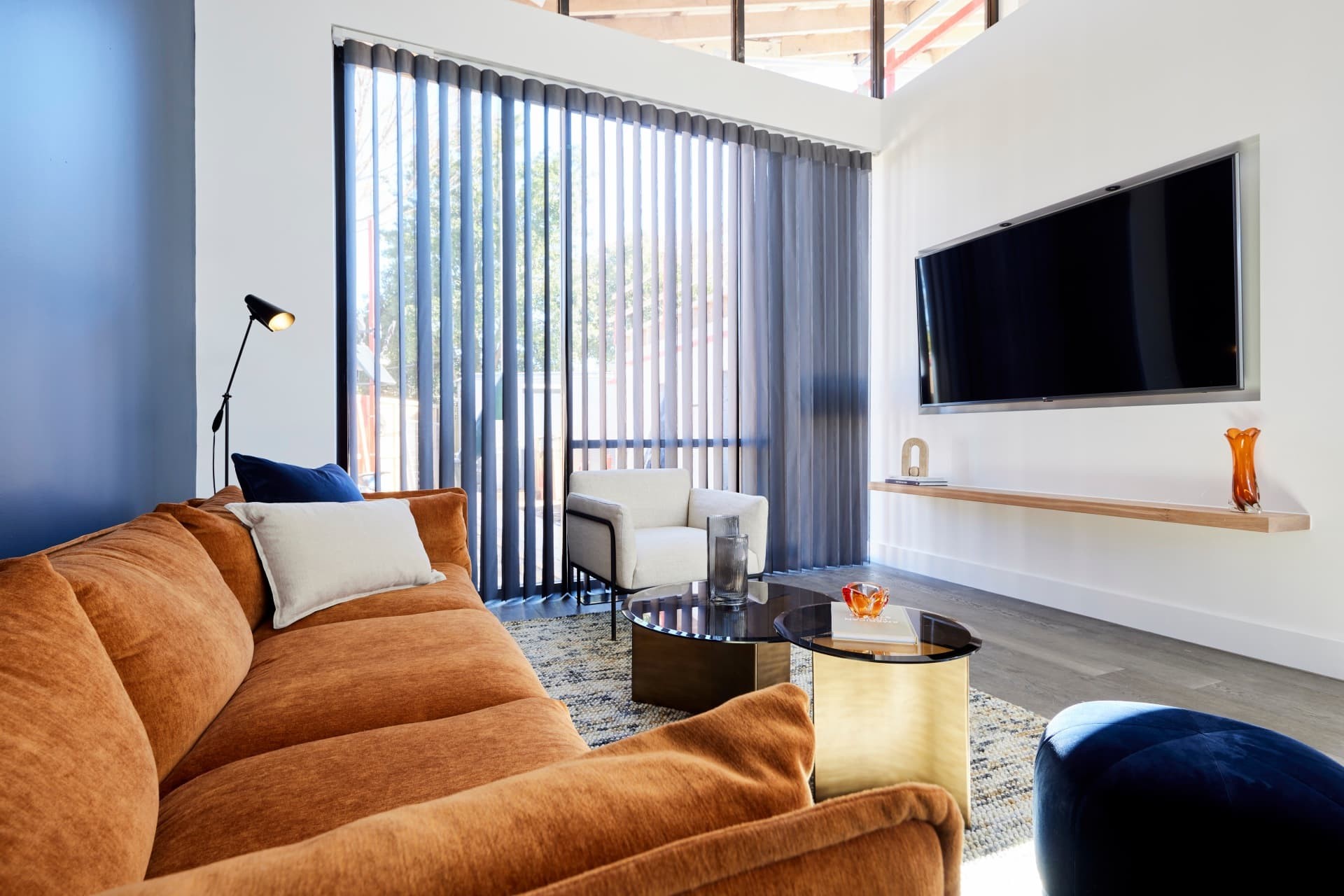 the block 2021 josh and luke living room with burnt orange sofa and black sheer curtains