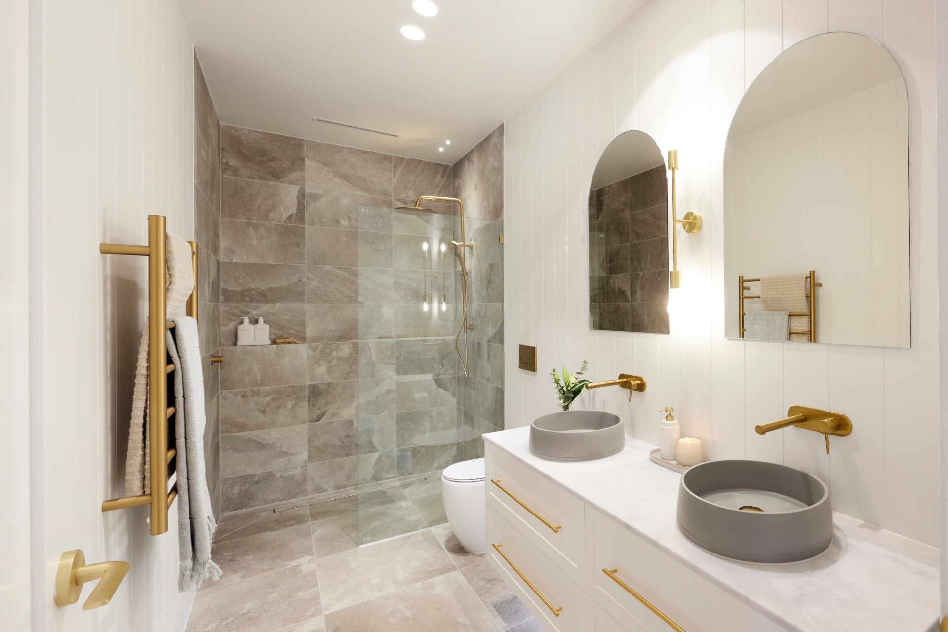 the block 2021 kirsty and jesse grey and white bathroom with brass accents arched mirrors