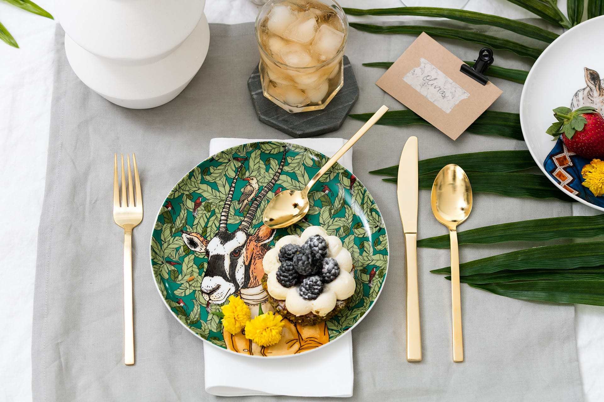 west elm goat plate with gold cutlery set and palm leaf on table