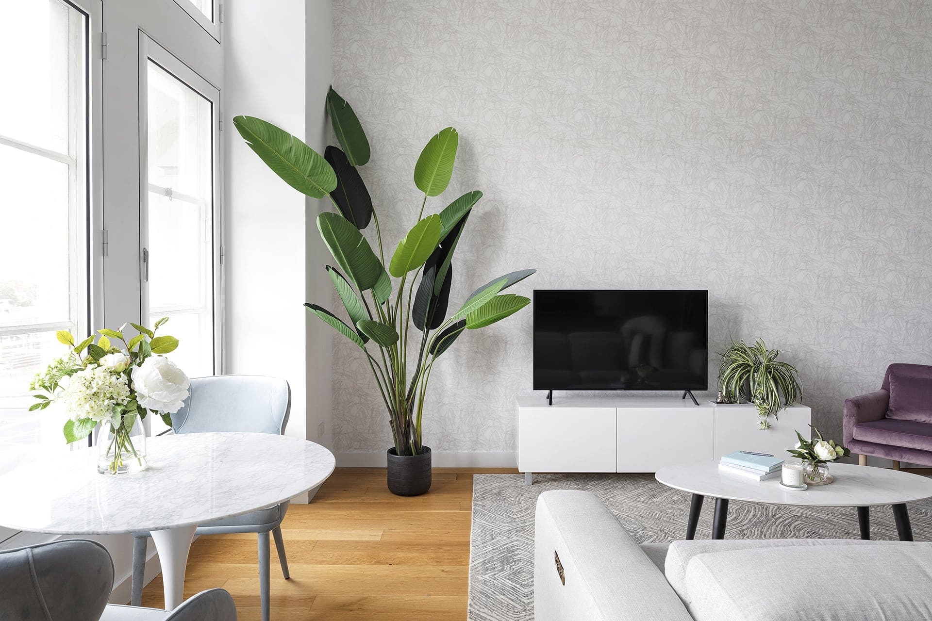white and grey wallpaper design in melbourne apartment living room with large fake bird of paradise plant