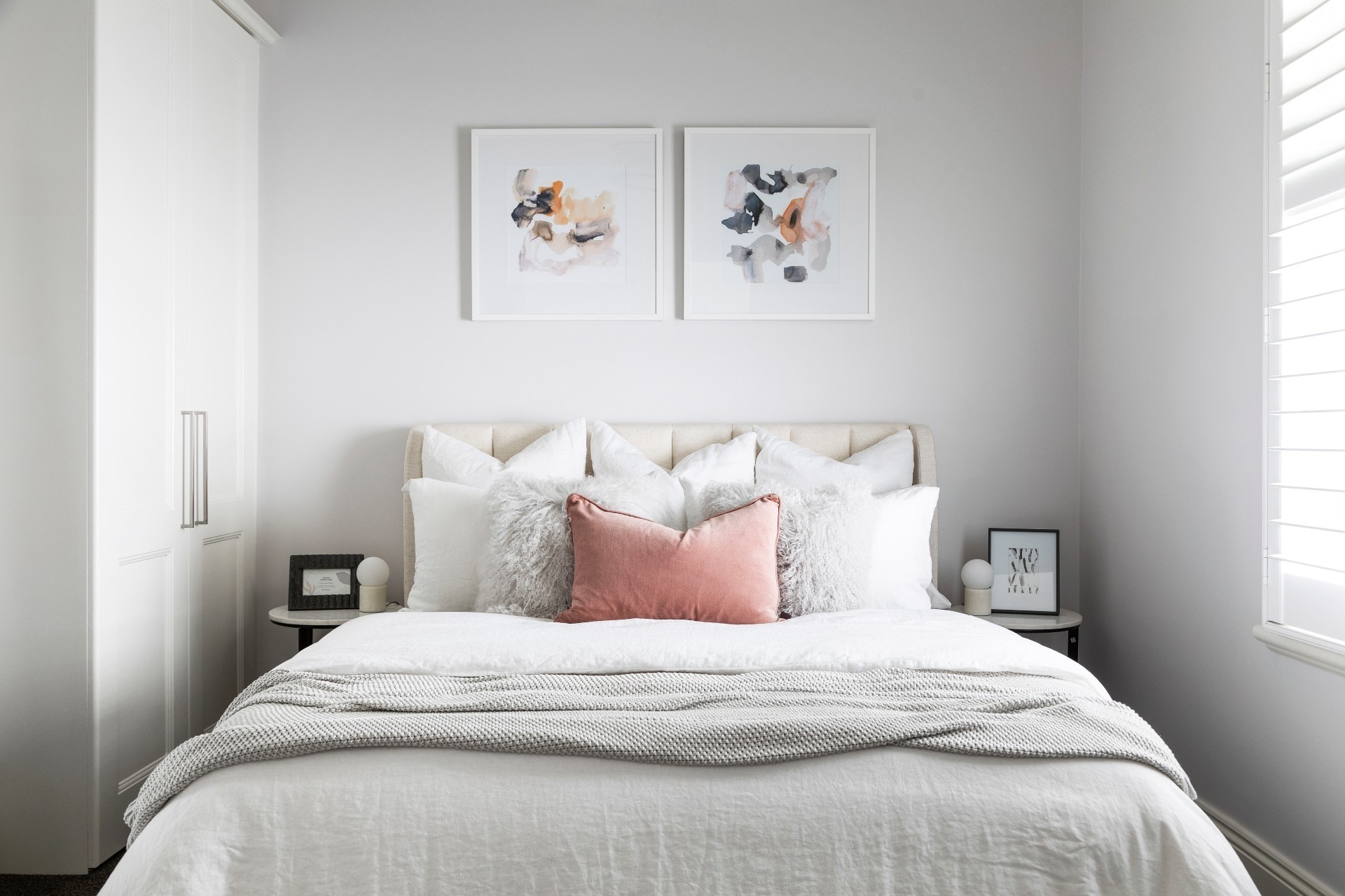 white guest bedroom with beige upholstered bed frame mongolian cushions and blush velvet cushion
