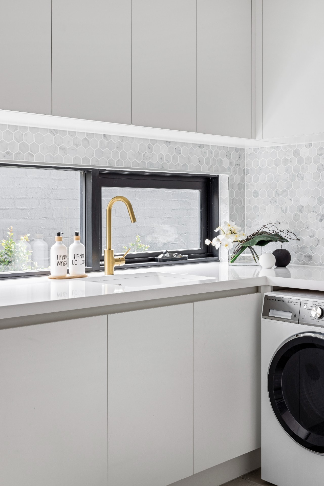 white laundry with hexagonal marble tiles and brass tapware